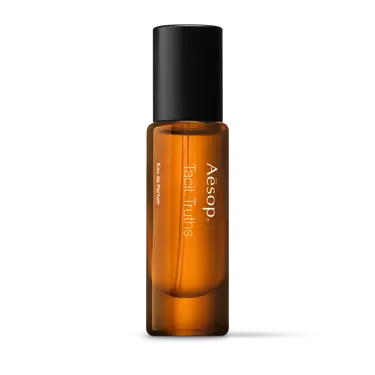 Aesop Tacit Truths in a slender amber fragrance bottle with white lettering and a tall black cap on a white background.