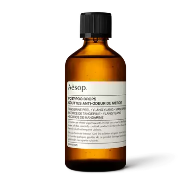 Aesop Post-Poo Drops in an amber bottle with rounded shoulders, a ribbed black cap and a cream label on a white background.