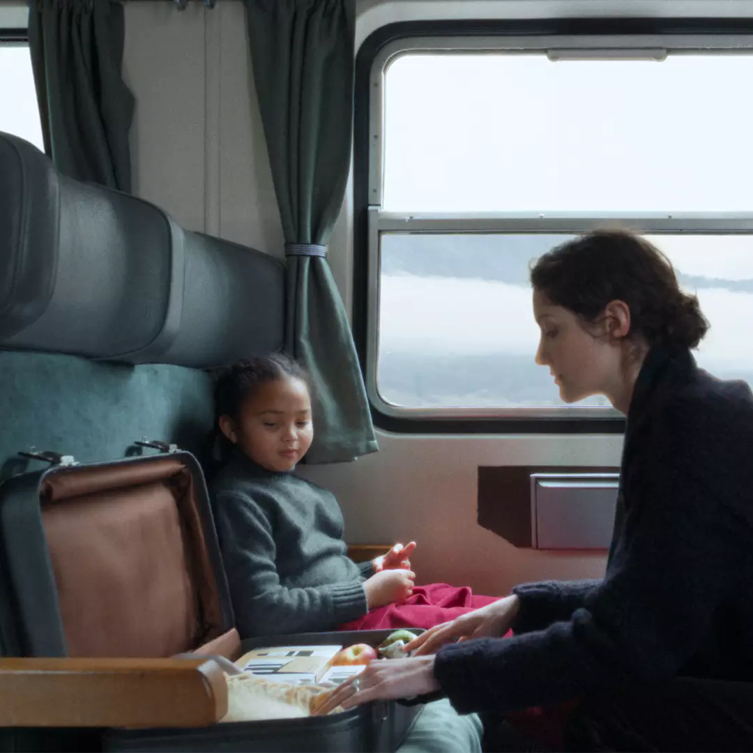 One person and one child on a train with a suitcase open