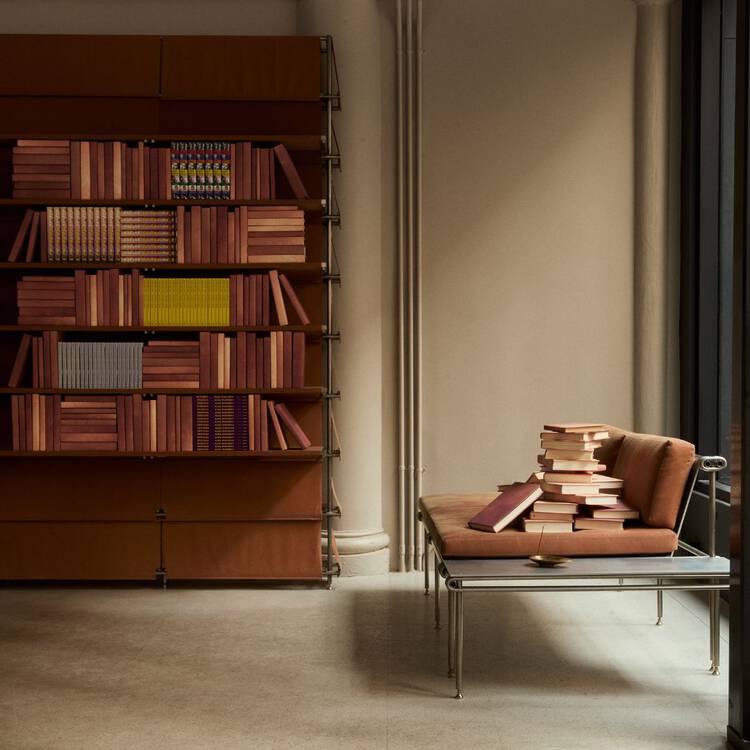 Small row of colourful books on a dark maroon shelf beside ribbed columns.
