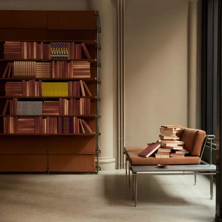 Small row of colourful books on a dark maroon shelf beside ribbed columns.
