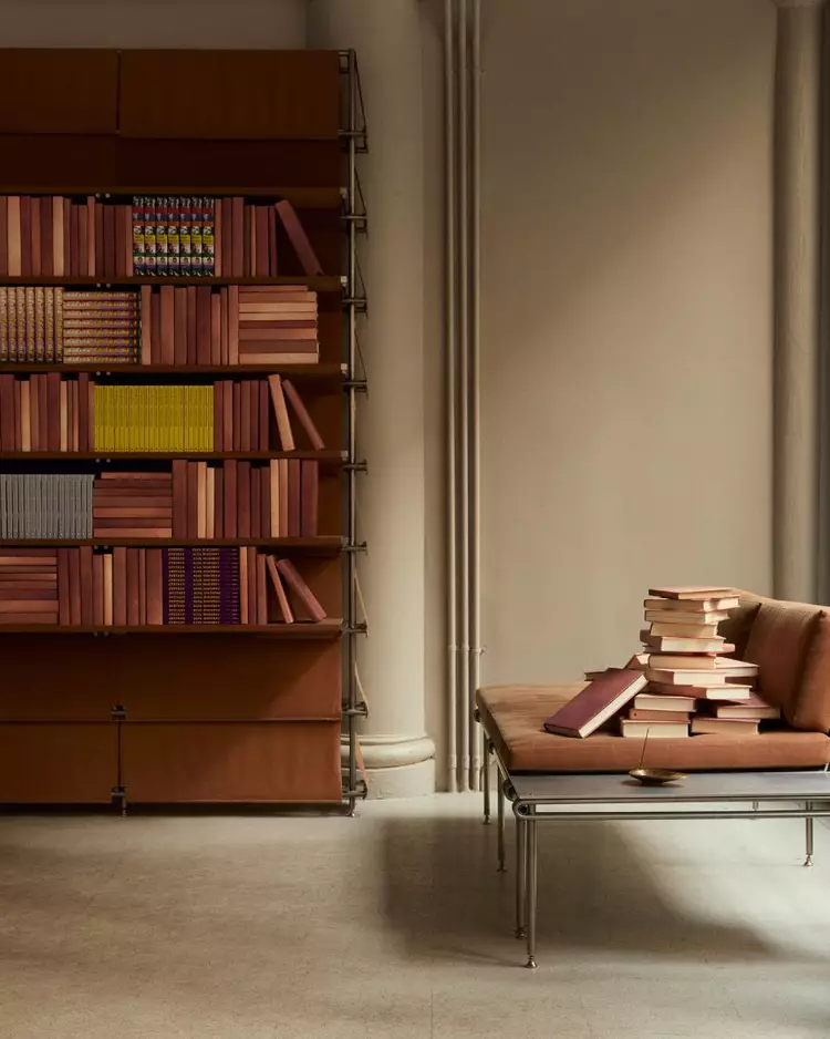 Small row of colourful books on a dark maroon shelf beside ribbed columns.