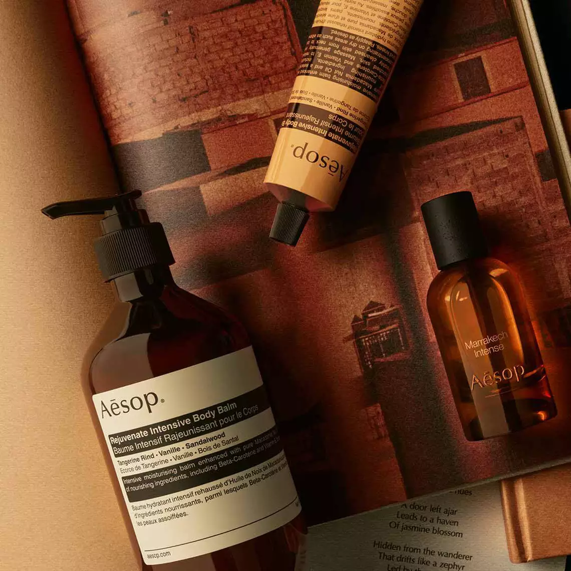 Aesop Marrakech Intense fragrance bottle, large pump bottle and wrapped product on a surface with Moroccan architecture in the background.
