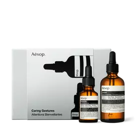 Two amber Aesop dropper bottles of different sizes stand in front of a silver-grey box illustrated with black bottle silhouettes.