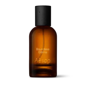 Amber glass Aesop Boundless Eremia Eau de Parfum bottle with black cap on a white background.