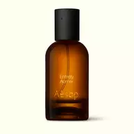 Amber glass Aesop Entirely Aurner Eau de Parfum bottle with black cap on a white background.