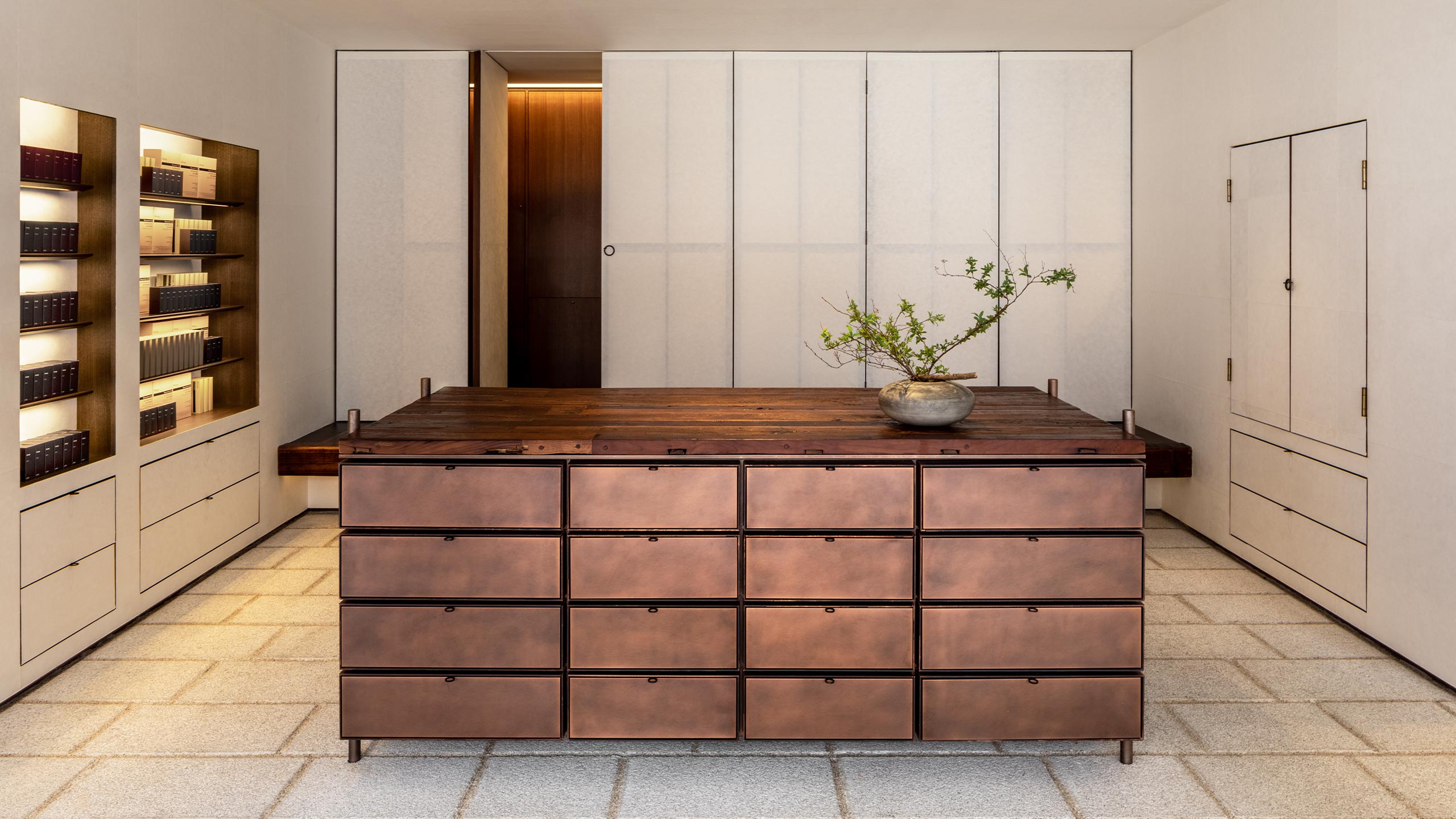 An aged copper basin with plant and a cabinet finished with reclaimed timber