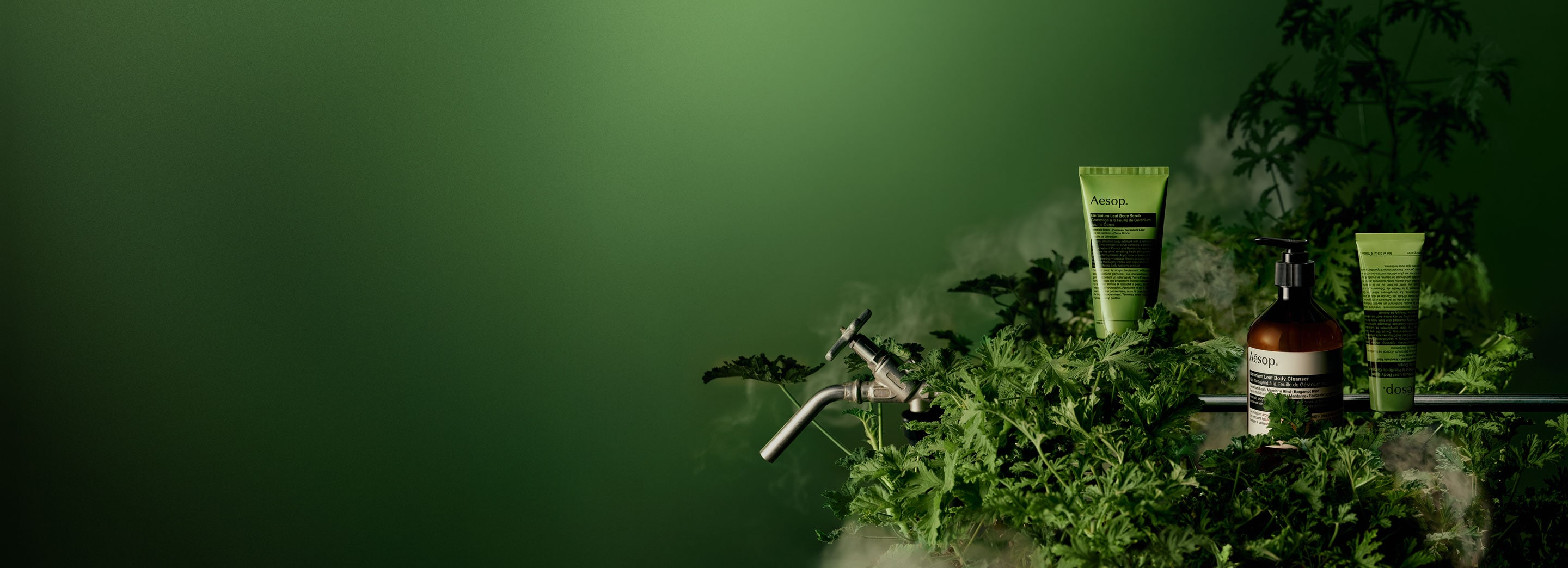 Geranium Leaf Body Scrub, Geranium Leaf Body Cleanser and Geranium Leaf Body Balm are displayed on a lush greenery background