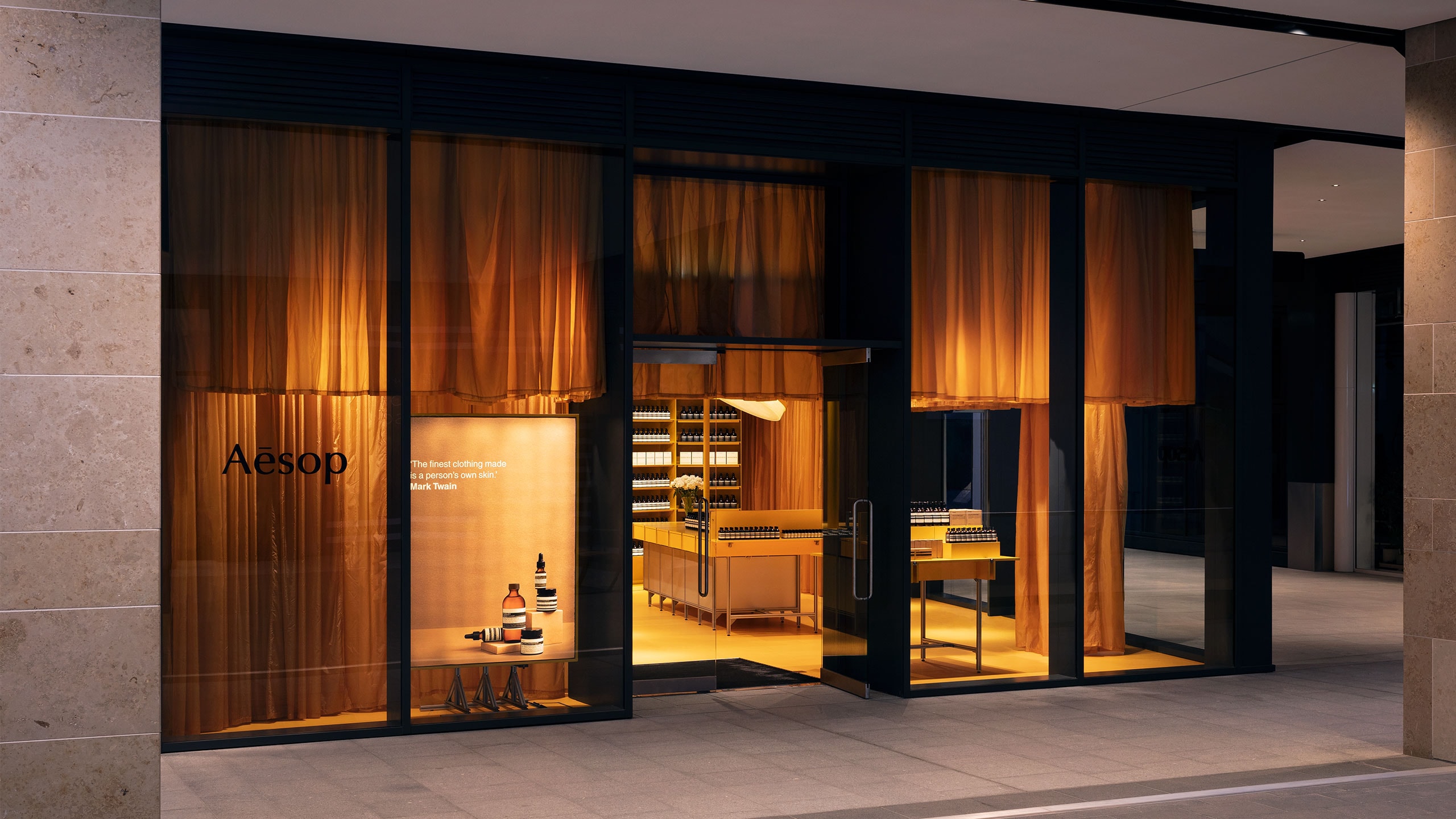 Exterior of Aesop St James store; exhibiting yellow translucent fabric behind the glass entrance.