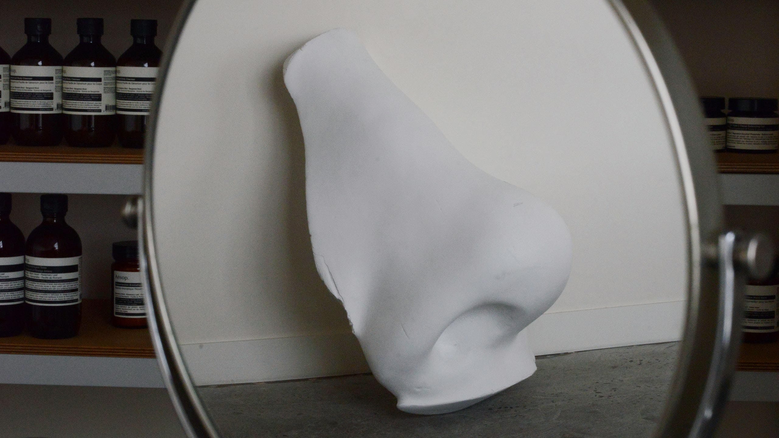An outsized plaster nose leaned against a wall, as seen via a mirror reflection.