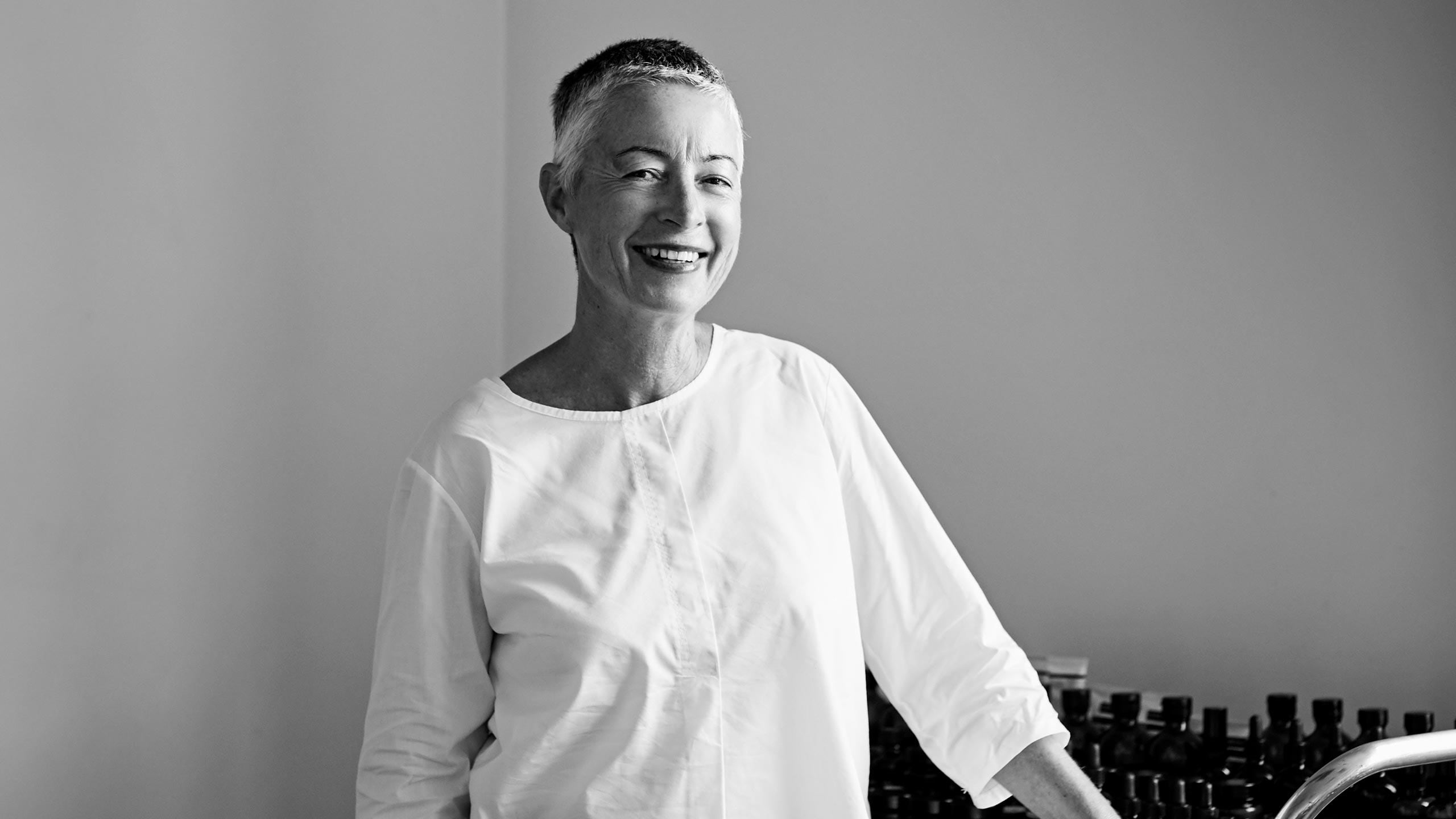 Aesop co-founder Suzanne Santos standing next to a countertop filled with Aesop products