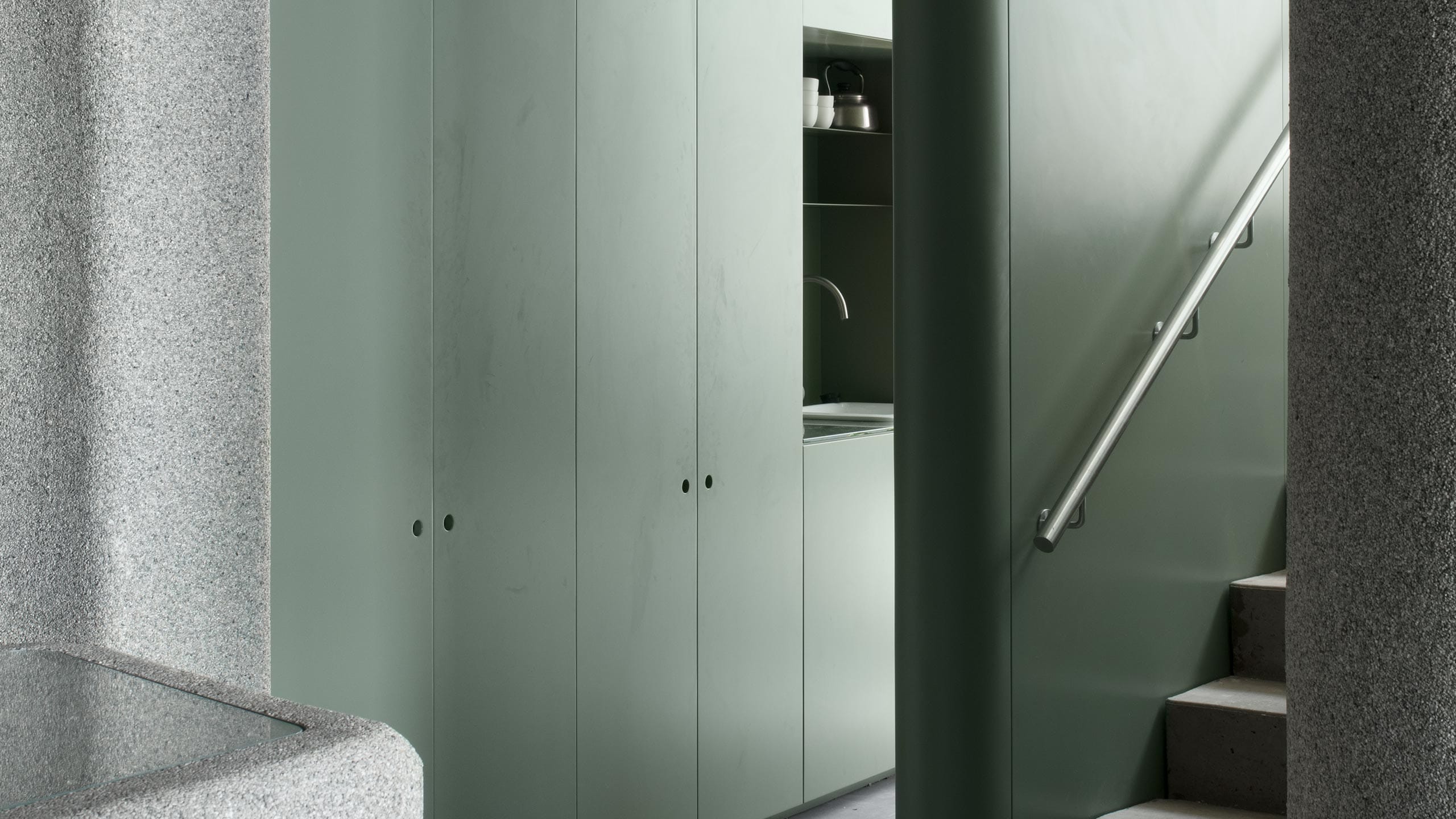 Pale green steel cupboards and a stairwell leading upwards.