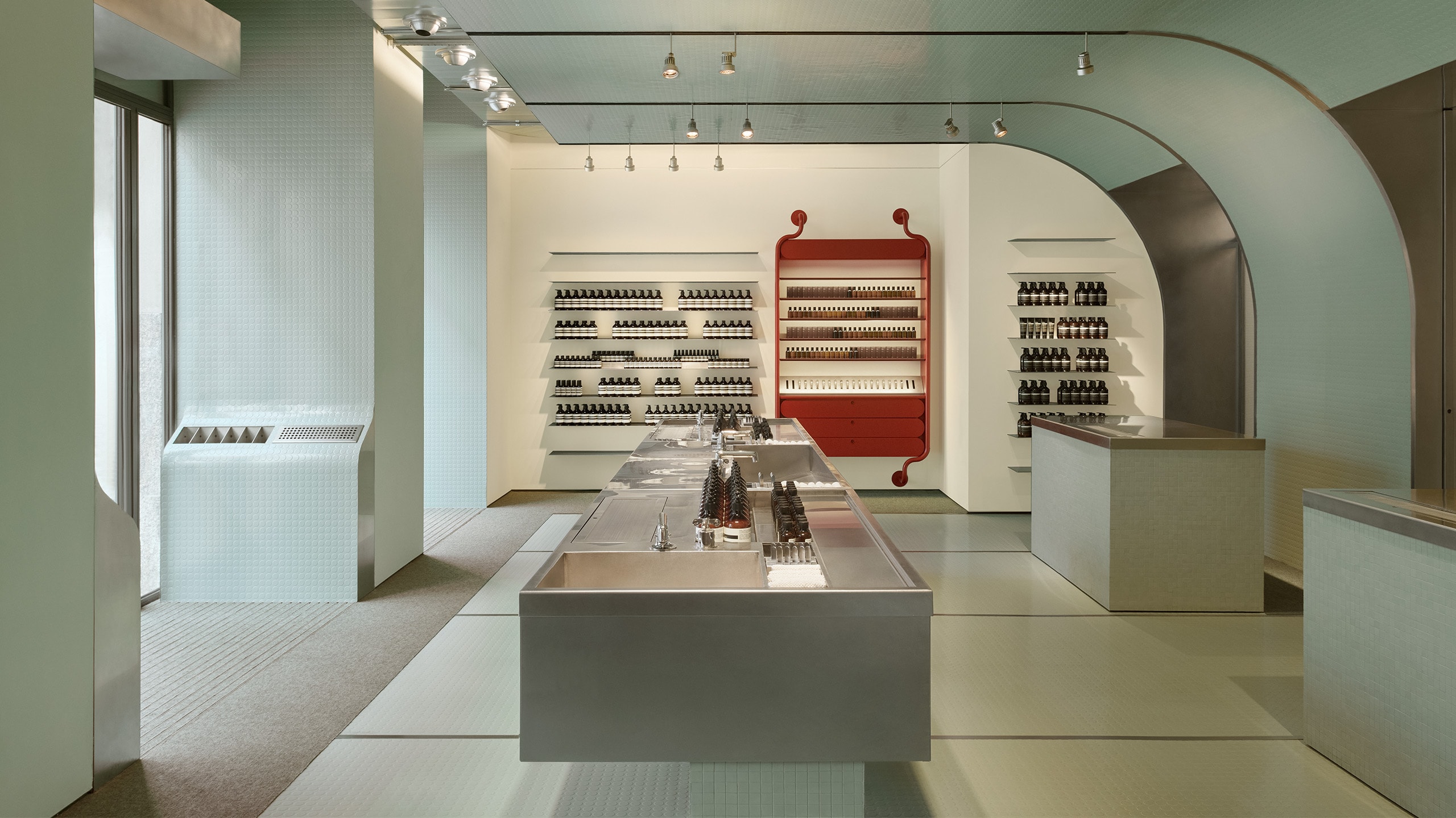 Aesop Milano Cordusio store interior made of rubber, stone and metal. Featuring the main basin and the alternate view of the bold red product display station.