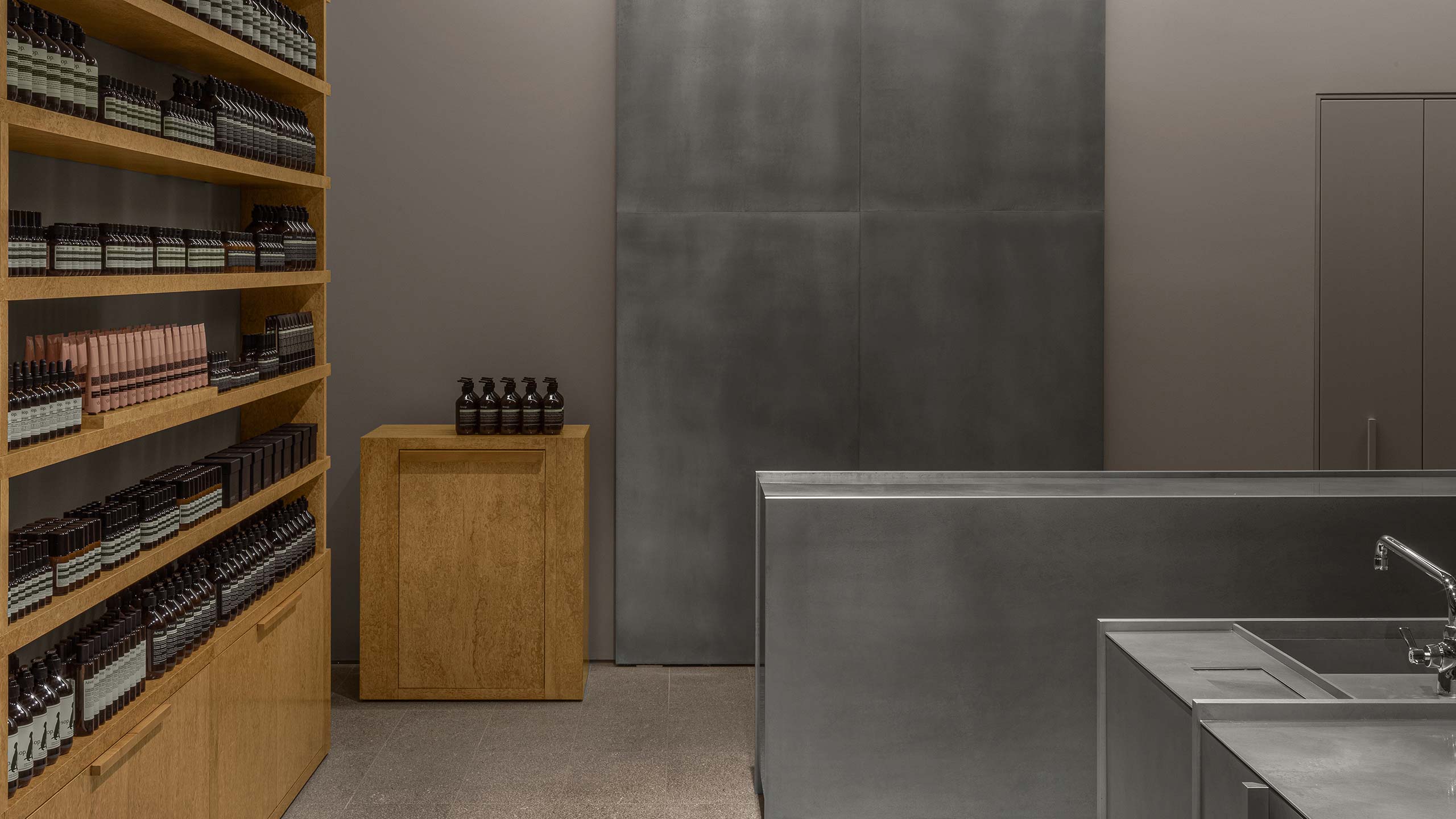 Aesop Yorkdale store interior, looking towards a metalic back wall with basin in foreground.