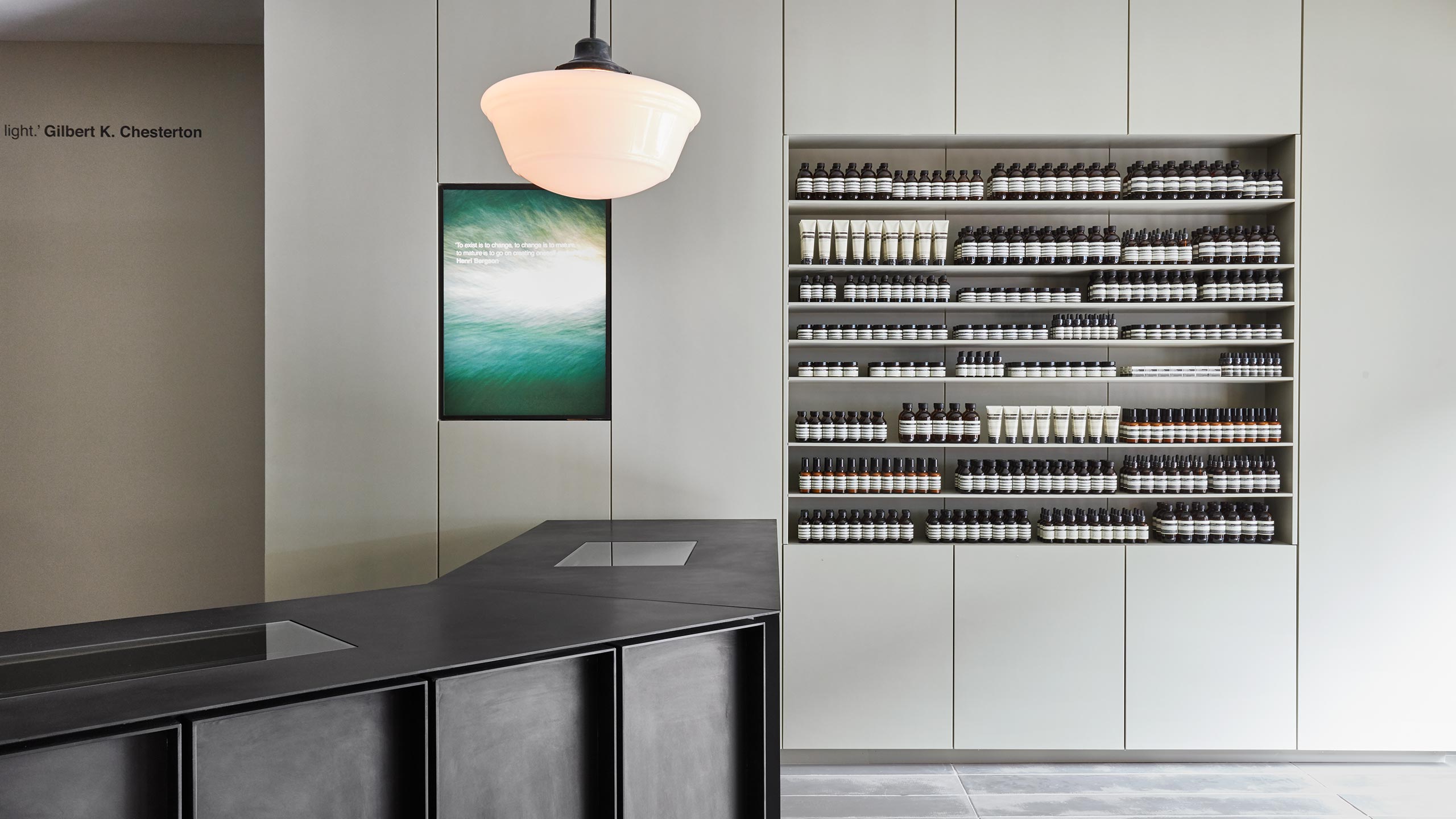 A steel black counter sitting against an off-white cabinet and shelving. 