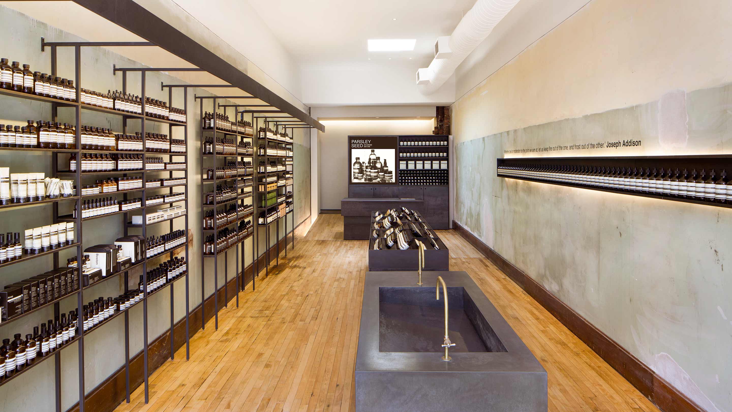 Black steel sinks sitting along the centre of Aesop Harvard Square store.