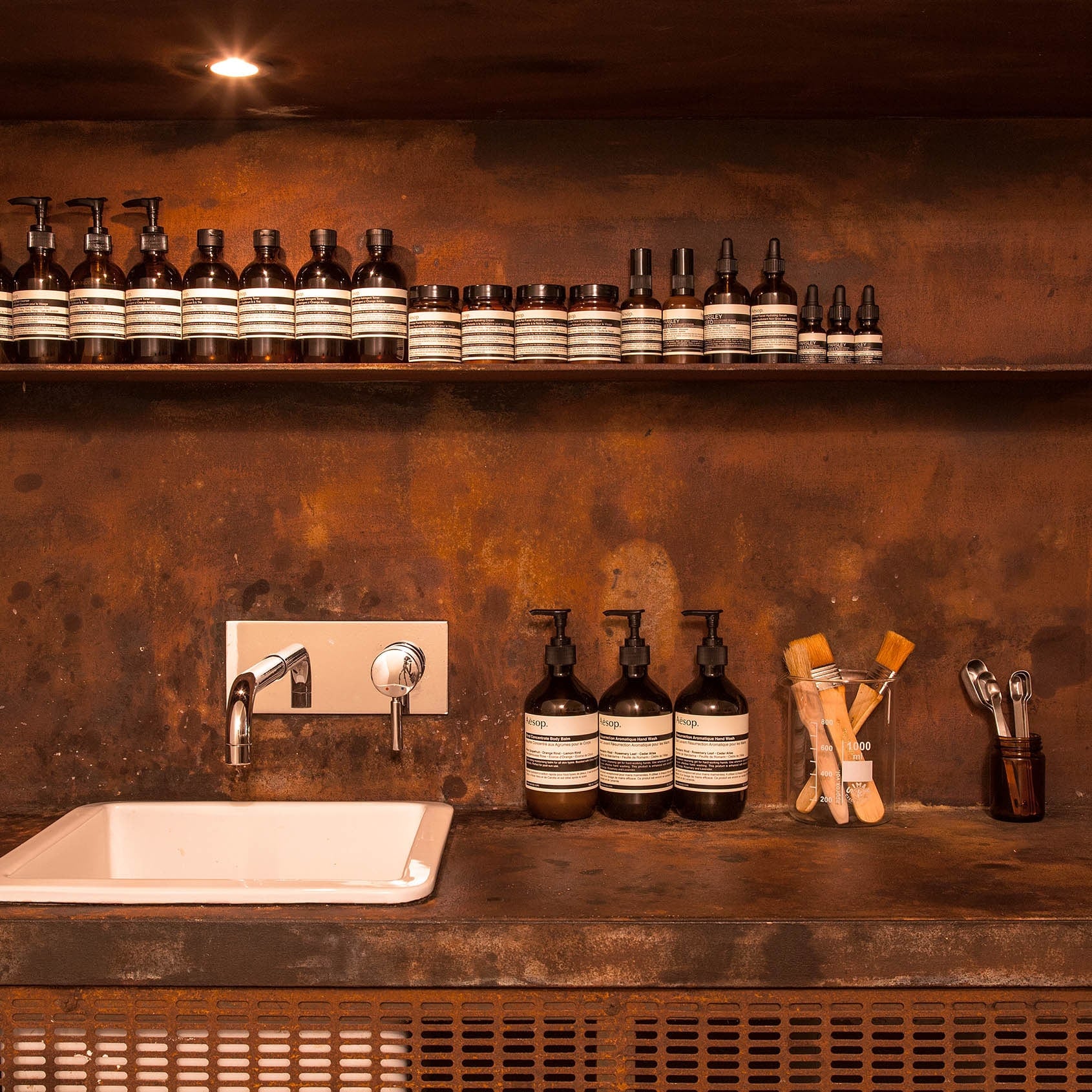 Close-up shot of basin area in an Aesop store, featuring products and applicators.