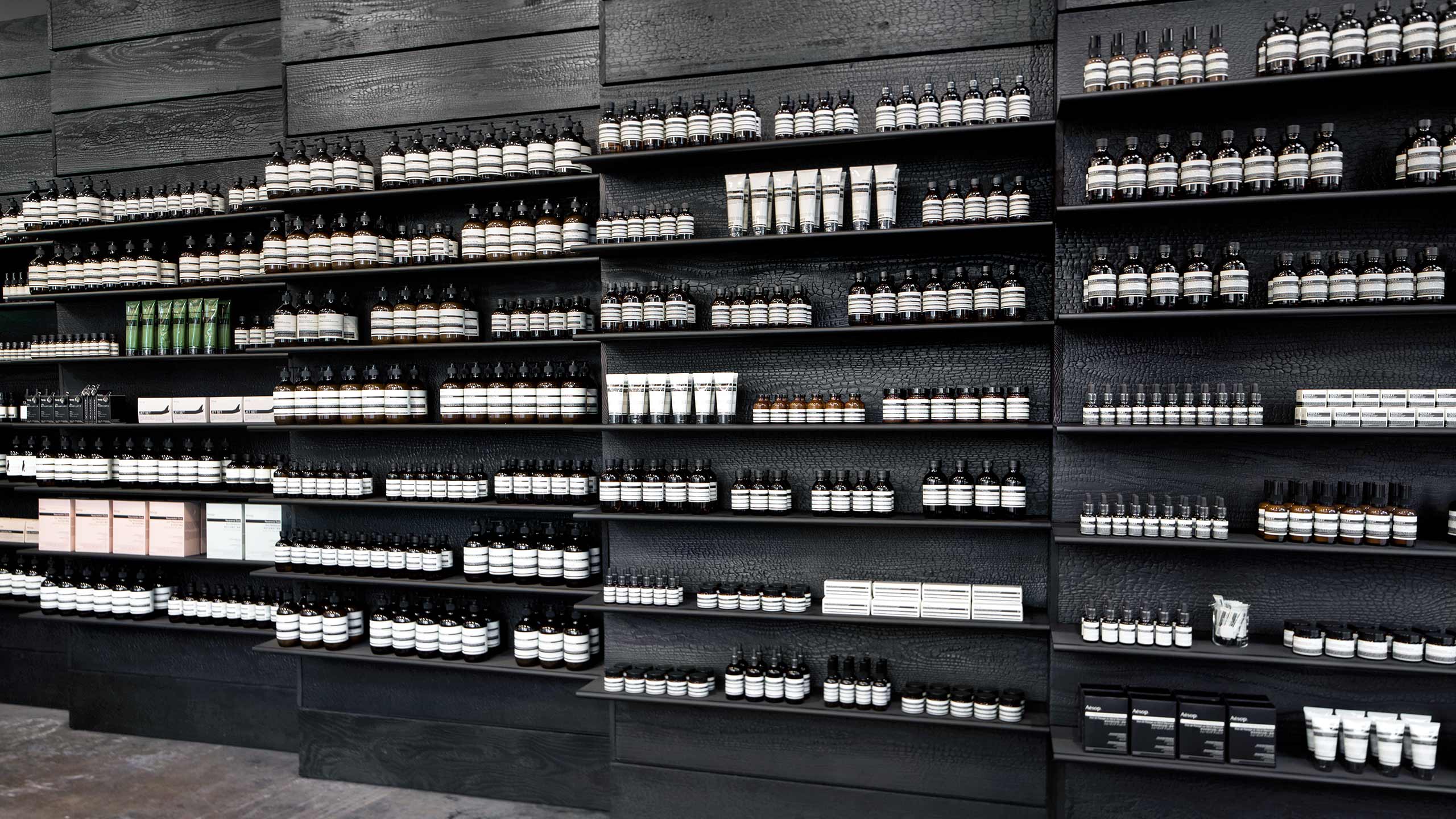 Black ash wooden shelves holding Aesop product.
