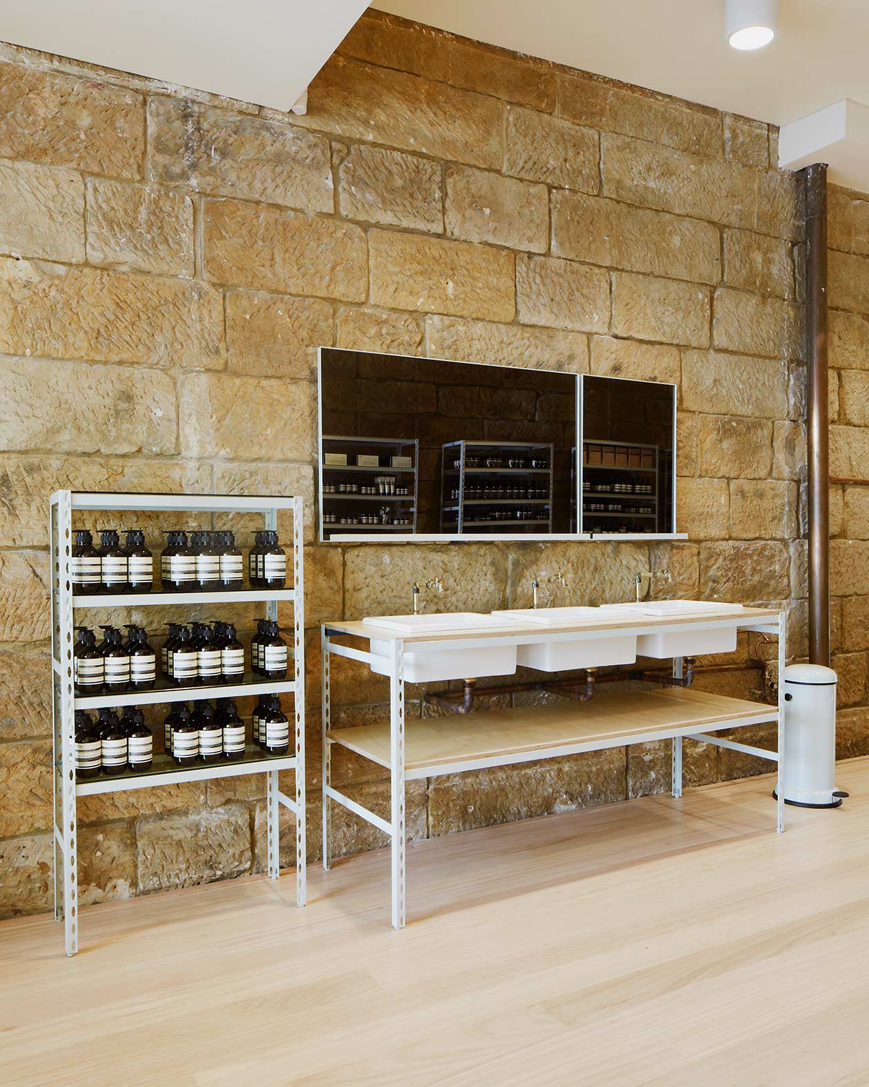 A customer service desk features three white porcelain basins. A dark mirror is positioned above.