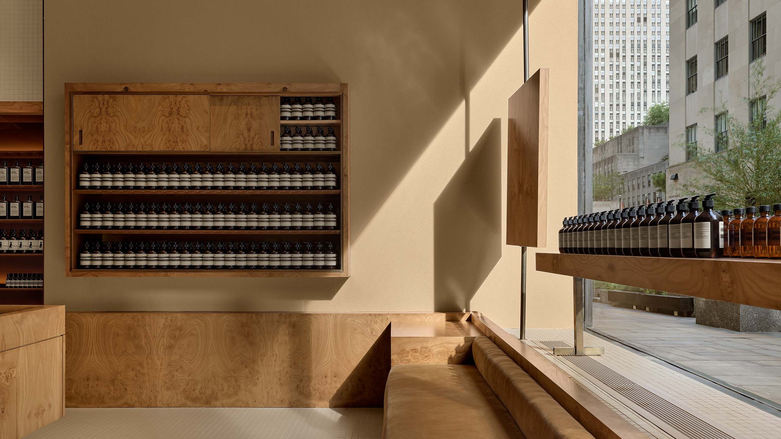 warmly decorated store interior with window on the right, and wooden cushioned bench and product shelves
