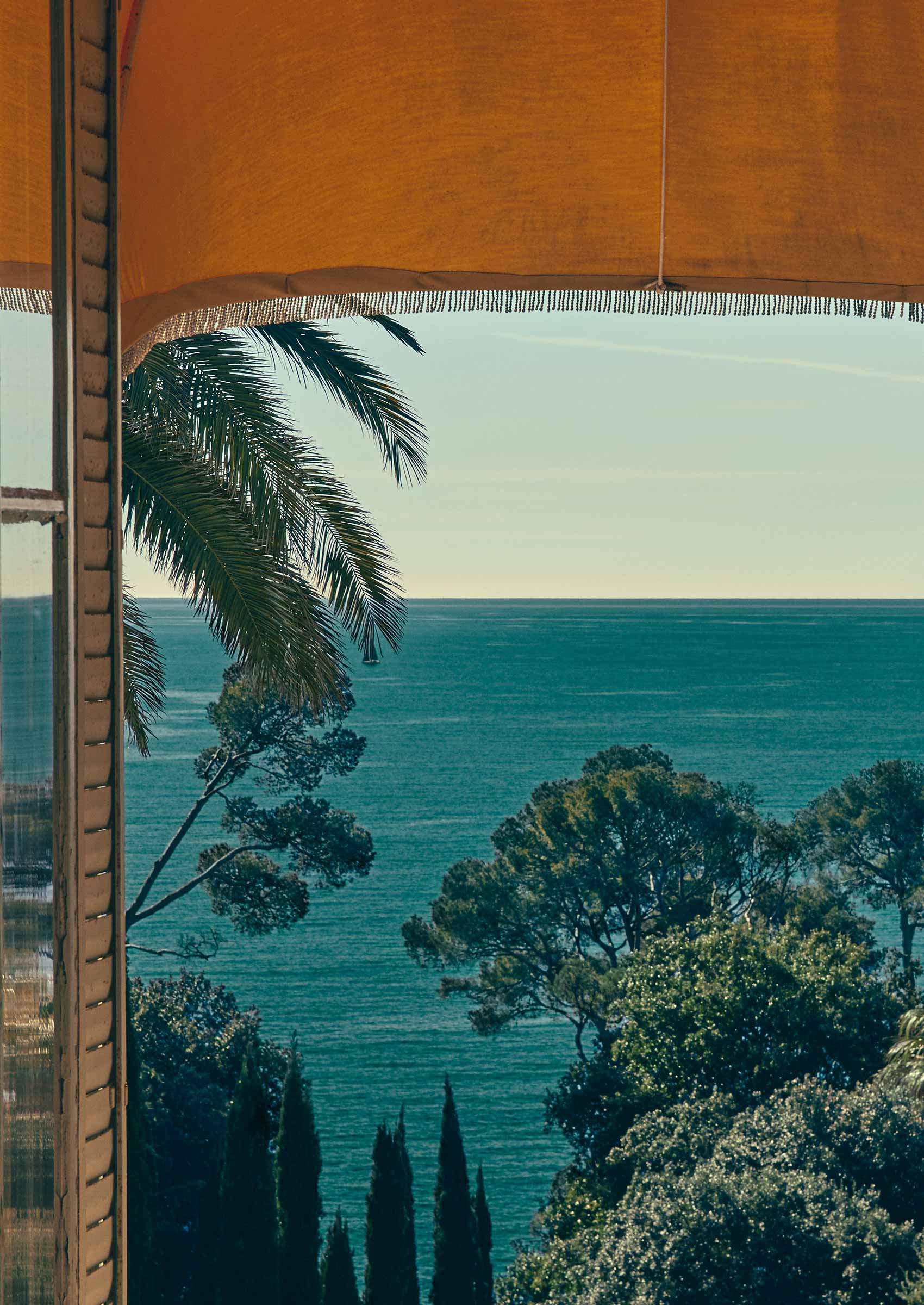 Paisaje oceánico visto desde ventanas de persiana abiertas.