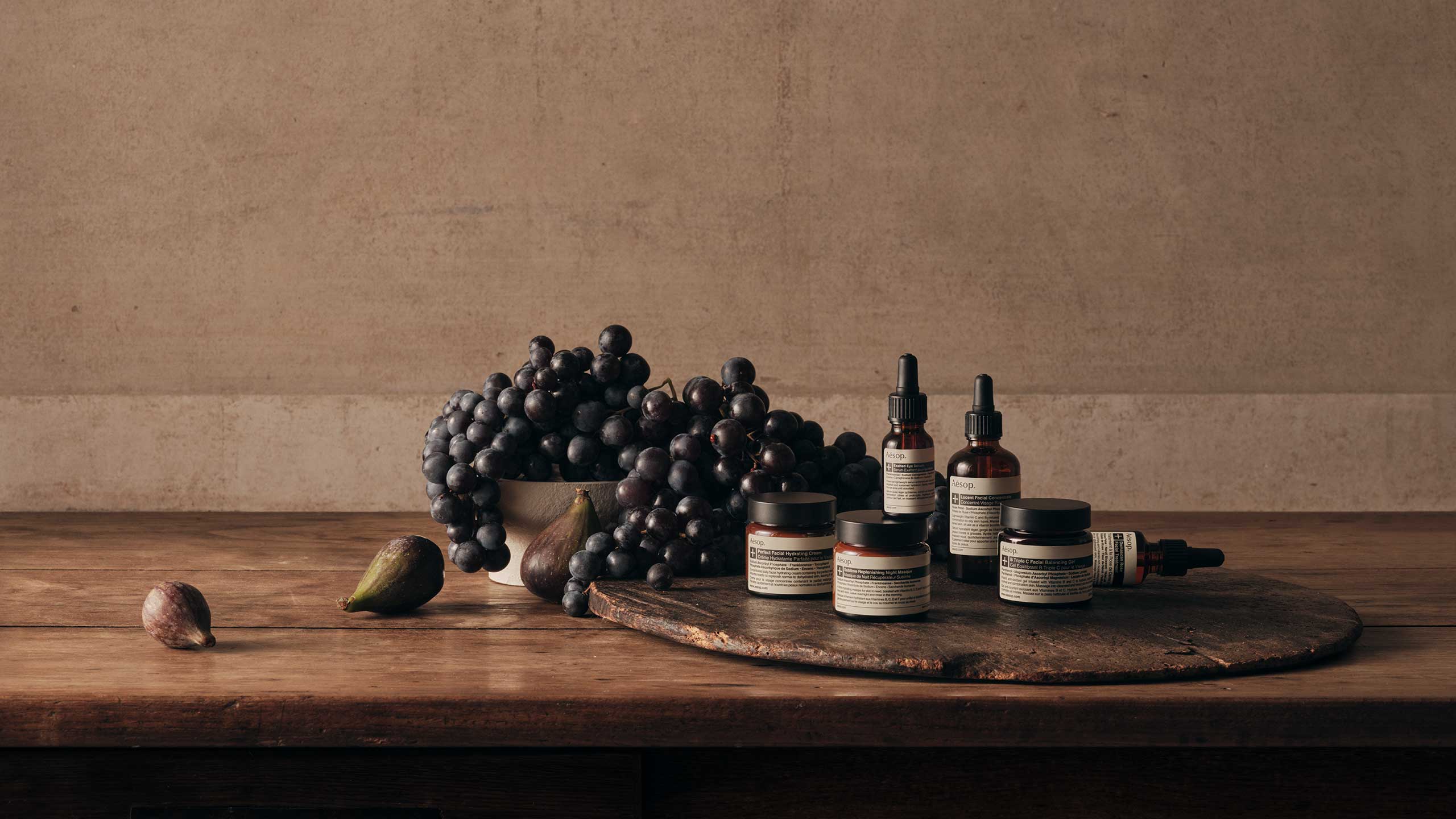 Aesop products sitting alongside a bowl of grapes and figs.