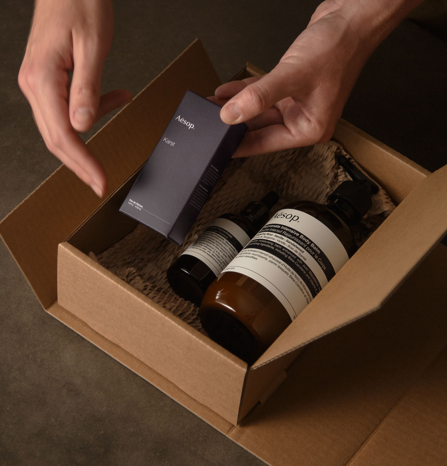 Hands of an Aesop consultant placing products into a carton.