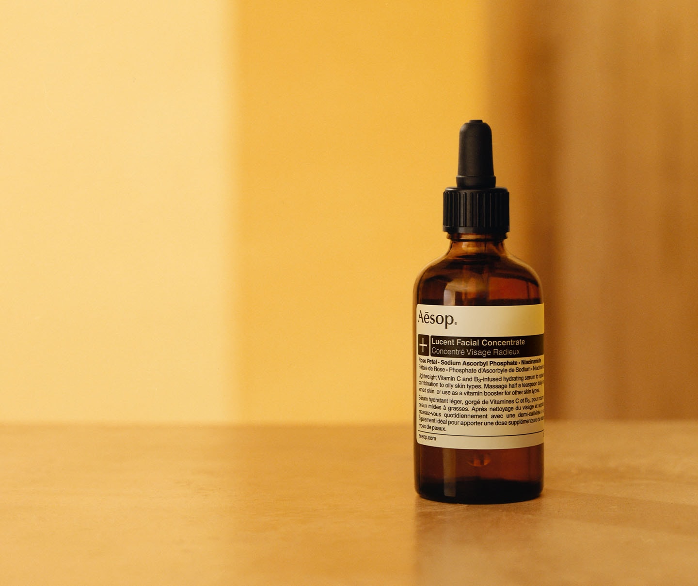 Lucent Facial Concentrate product in front of yellow fabric background.