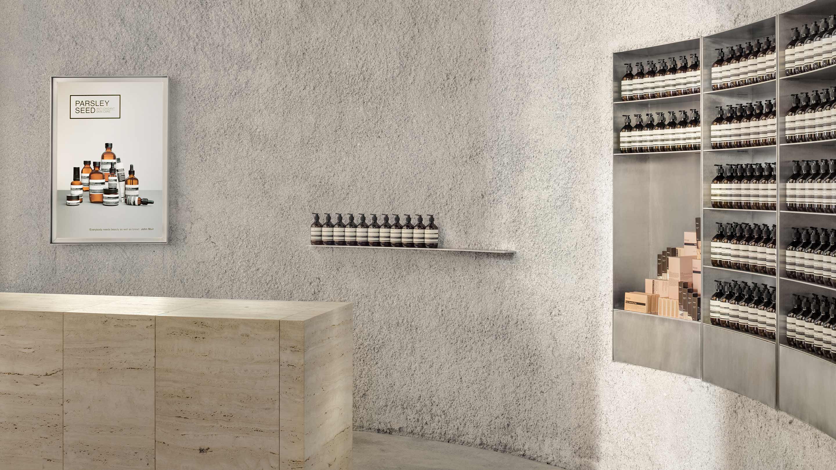An off-white curved textured wall surrounds the front counter inside Aesop North Bridge