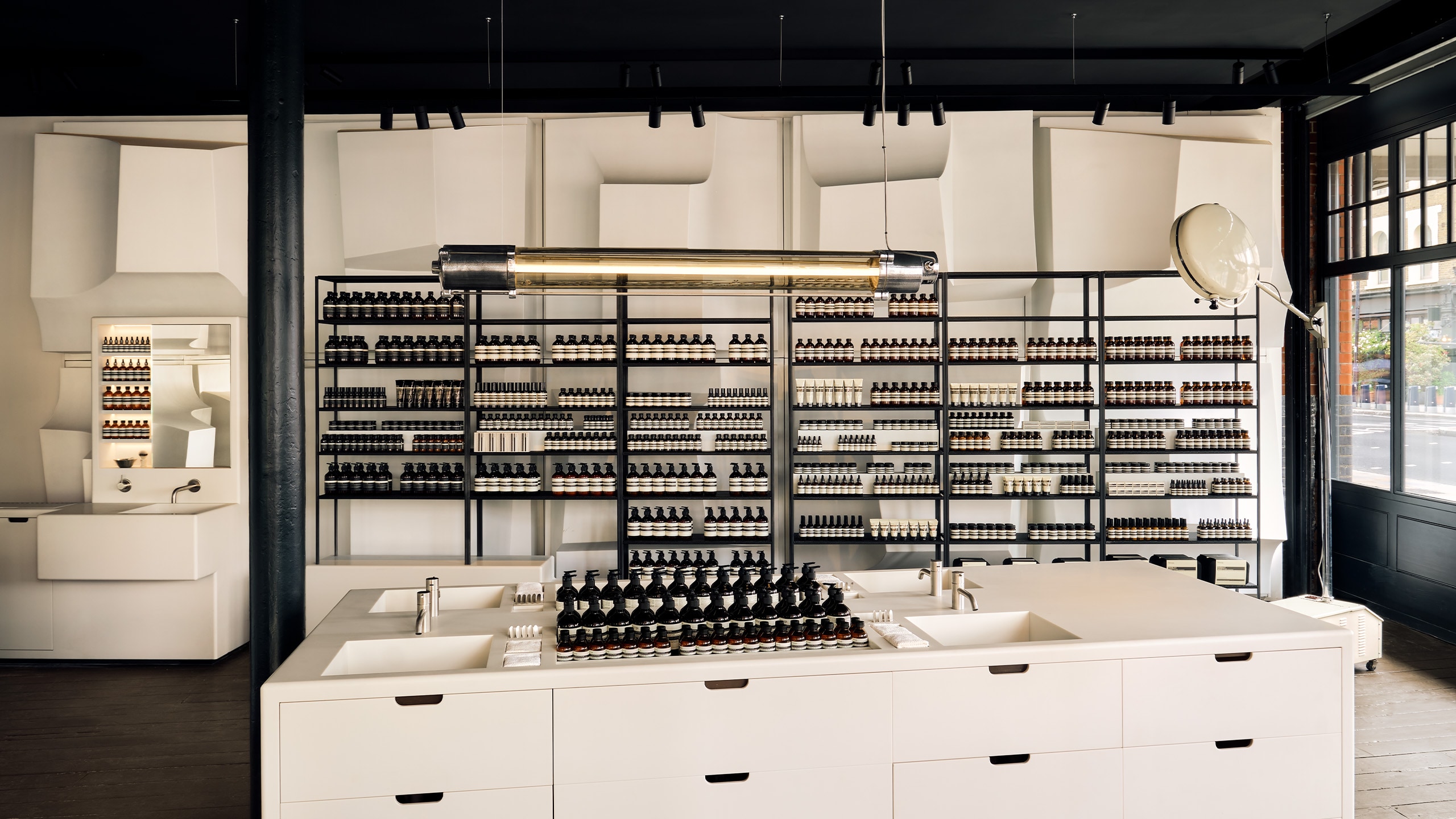 Aesop Spitalfields store interior displaying the central basins, cast in luminous white, customers are encouraged to explore the brand’s full range of formulations, with flowing water if desired.