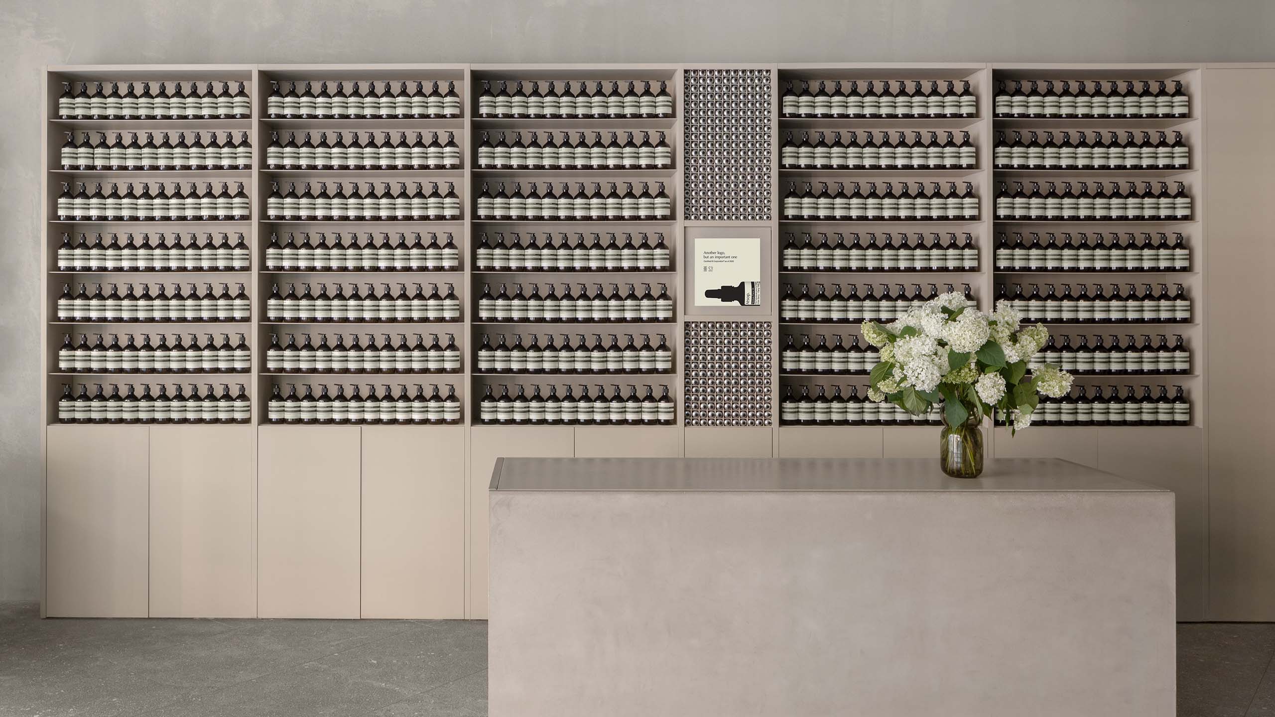 Aesop Eaton Toronto Store Counter with a flower arrangement on top and amber bottle display in the background