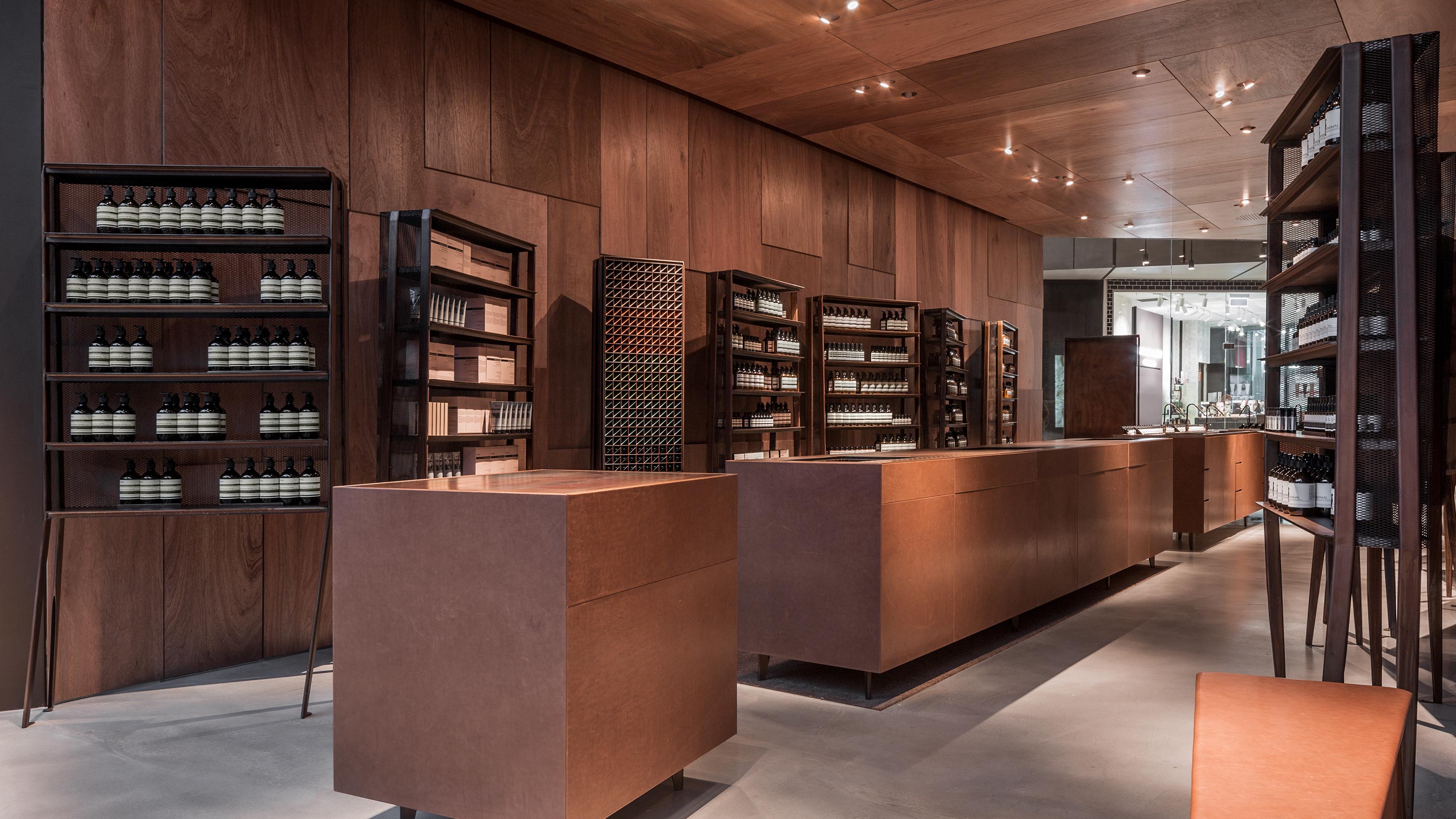 A dim, woody interior with brushed concrete flooring. Wooden counters line the timber walls of the store.