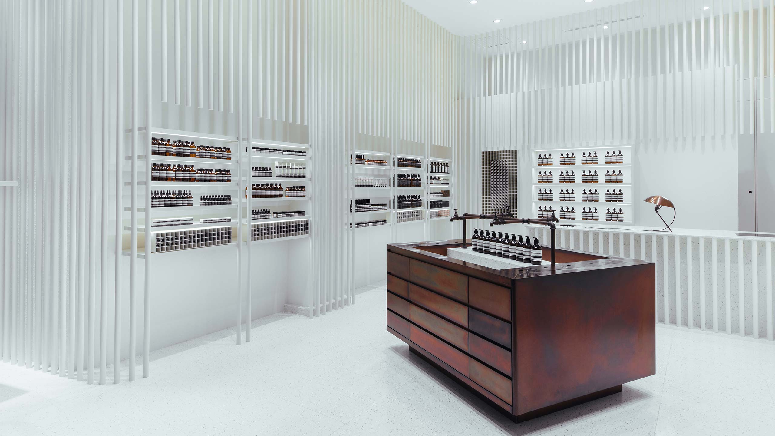 A freestanding dark-copper basin juxtaposed with the clean white store interior. 