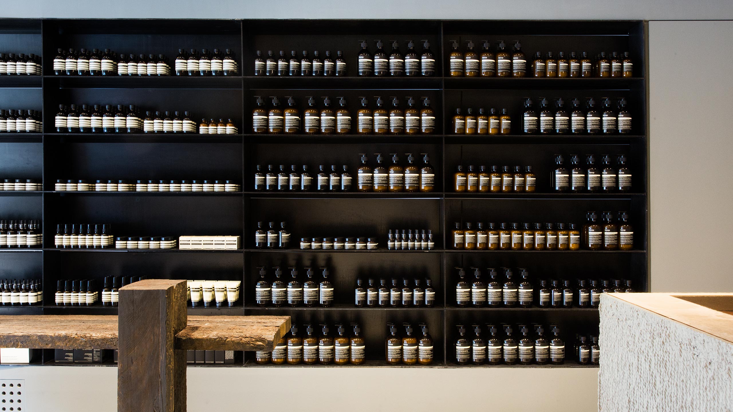 Rows of Aesop product sitting on black shelves