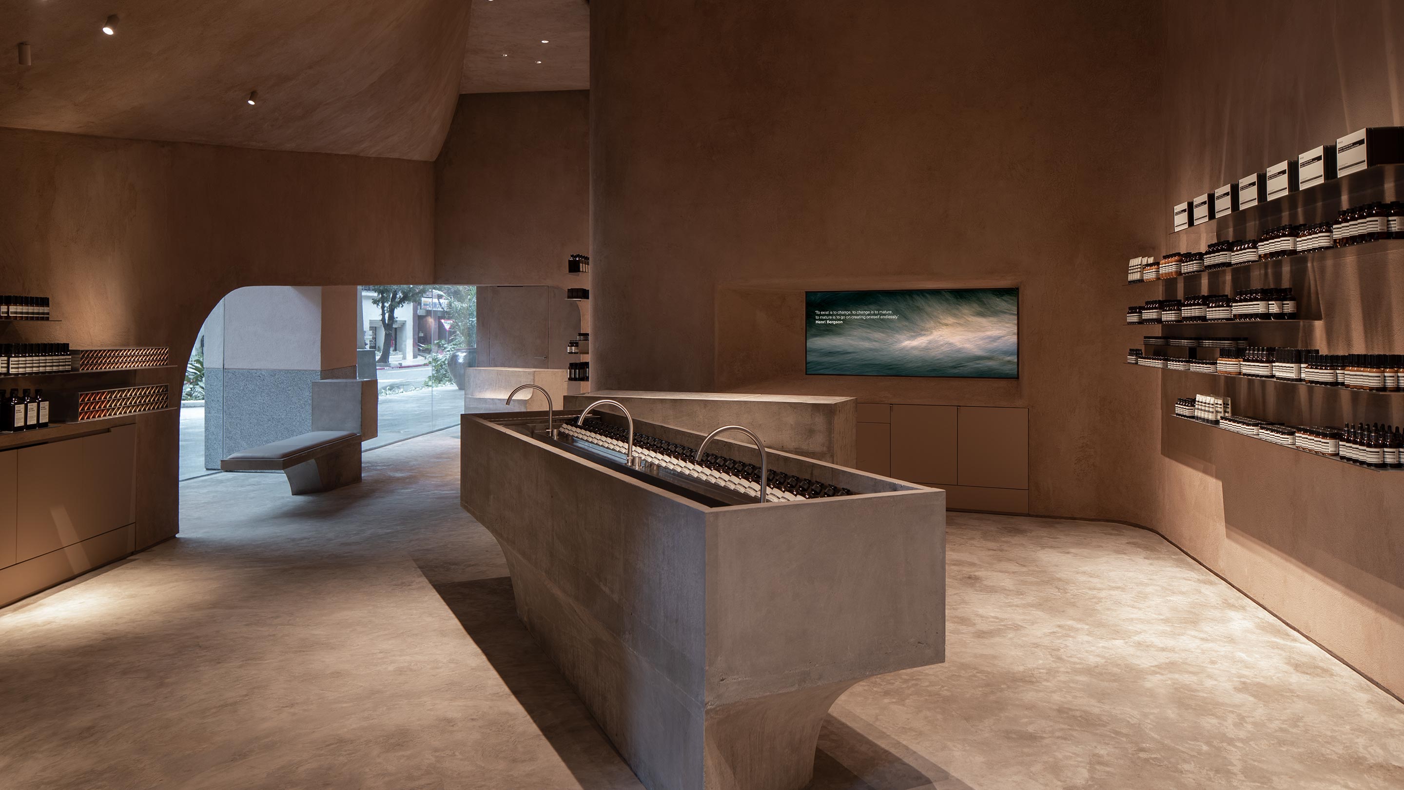 Dusty beige and grey Interior of the store featuring brushed concrete flooring, basins and counters. 