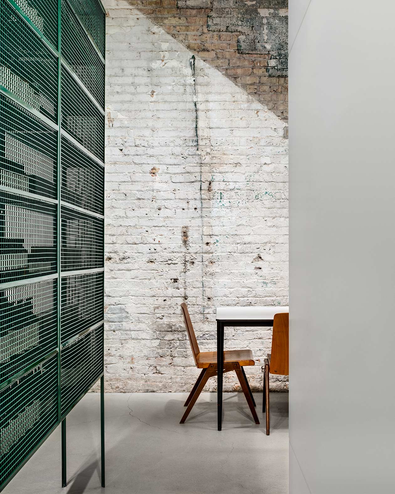 A mid-century table and chair sit by a white, textured brick wall.