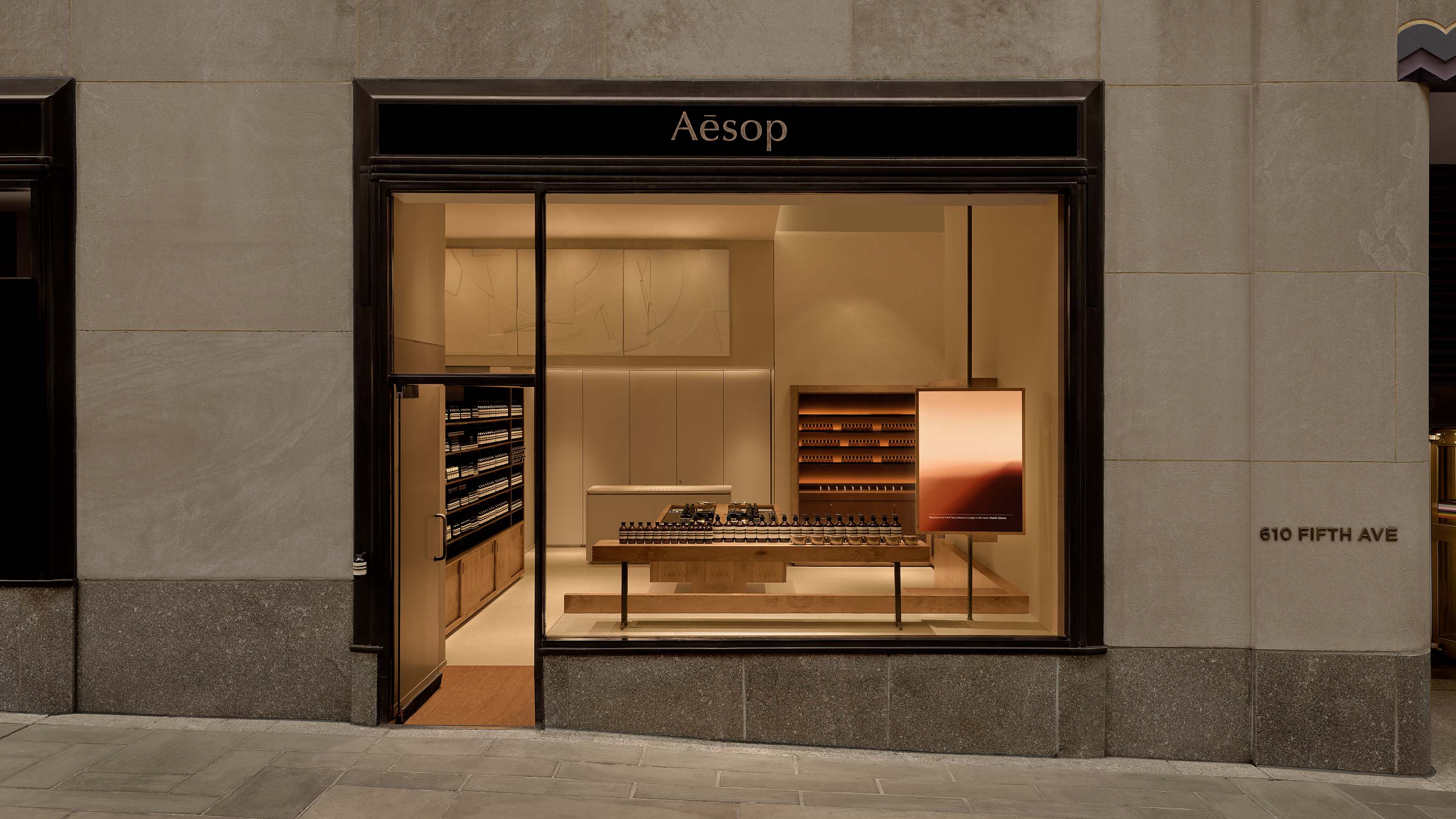 storefront featuring large window in cement brick wall looking into warmly lit interior