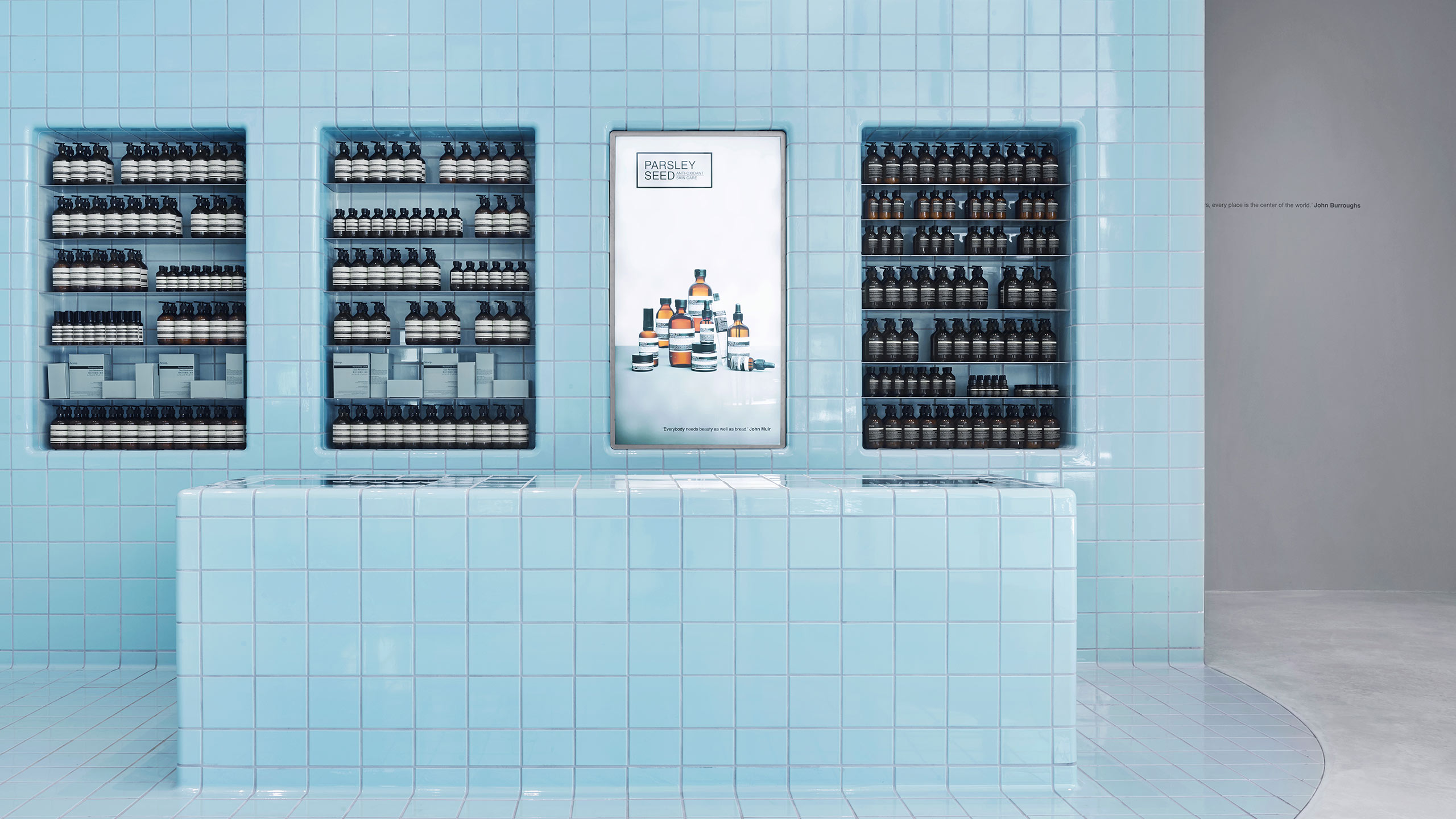 A light-blue tiled store counter; a light box fitted is fitted on the wall behind. 