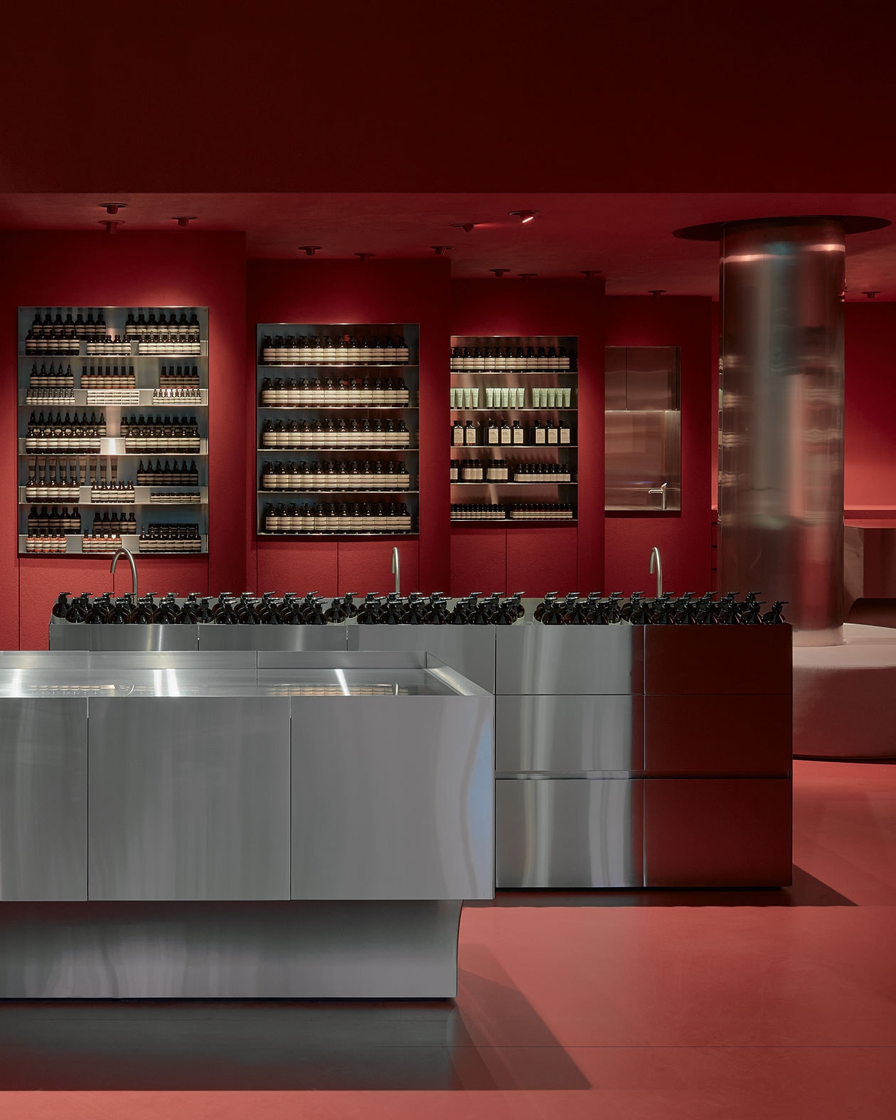 Brushed stainless steel customer service counter surrounded by dark red walls.