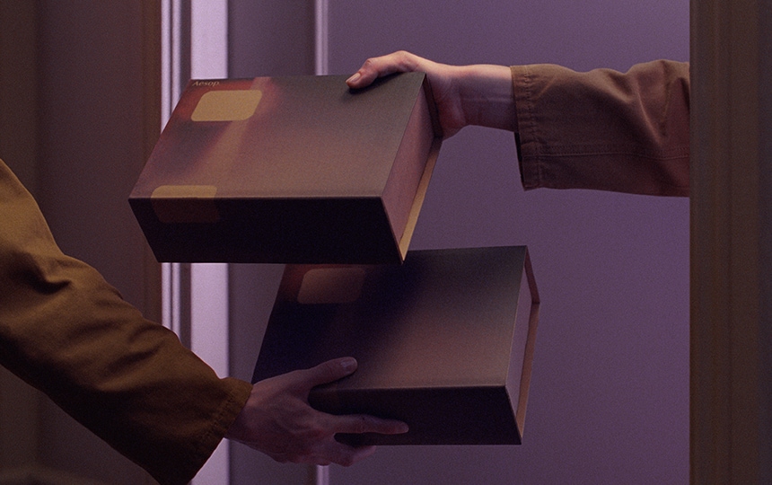 two hands exchanging purple gift boxes through an open door, with background shaded by purple filter