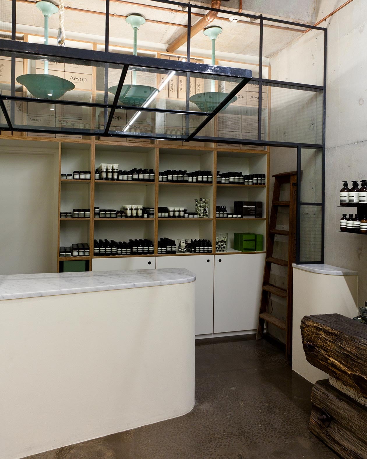 White customer service counter with marble counter-top. Glass panes above it show three hanging vintage lights.