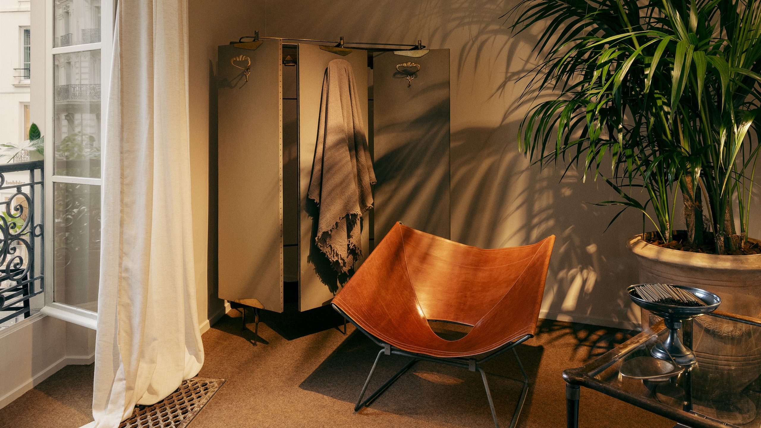 Aesop Rue de Sèvres store interior corner reflection space including a chair, window, plants and home scents.