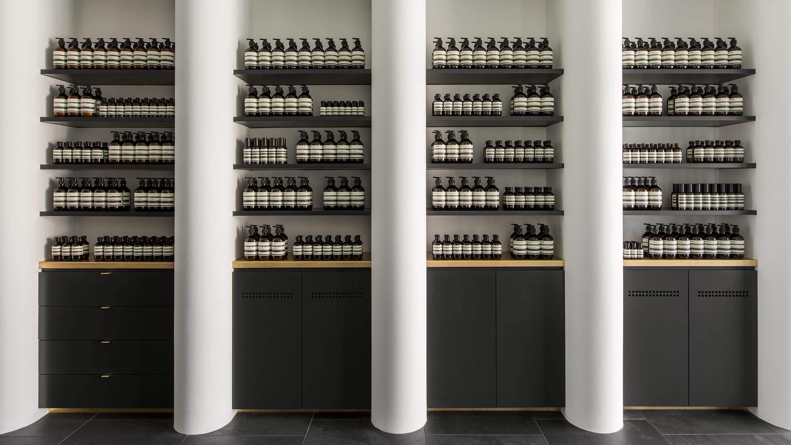 Aesop Studio City store interior, with 4 sets of products shelves, separated by large white columns.