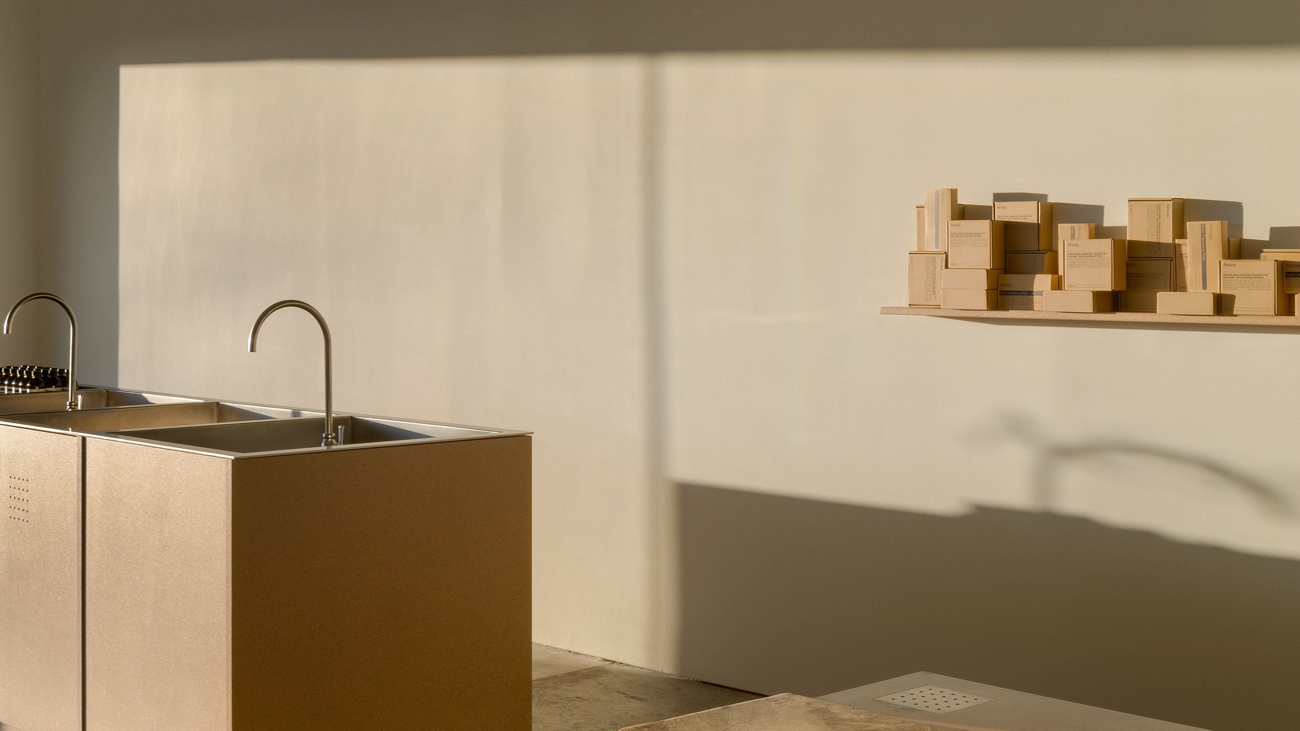Aesop Berkeley store interior, with sun past a set of basins leaving shadows on a wall.