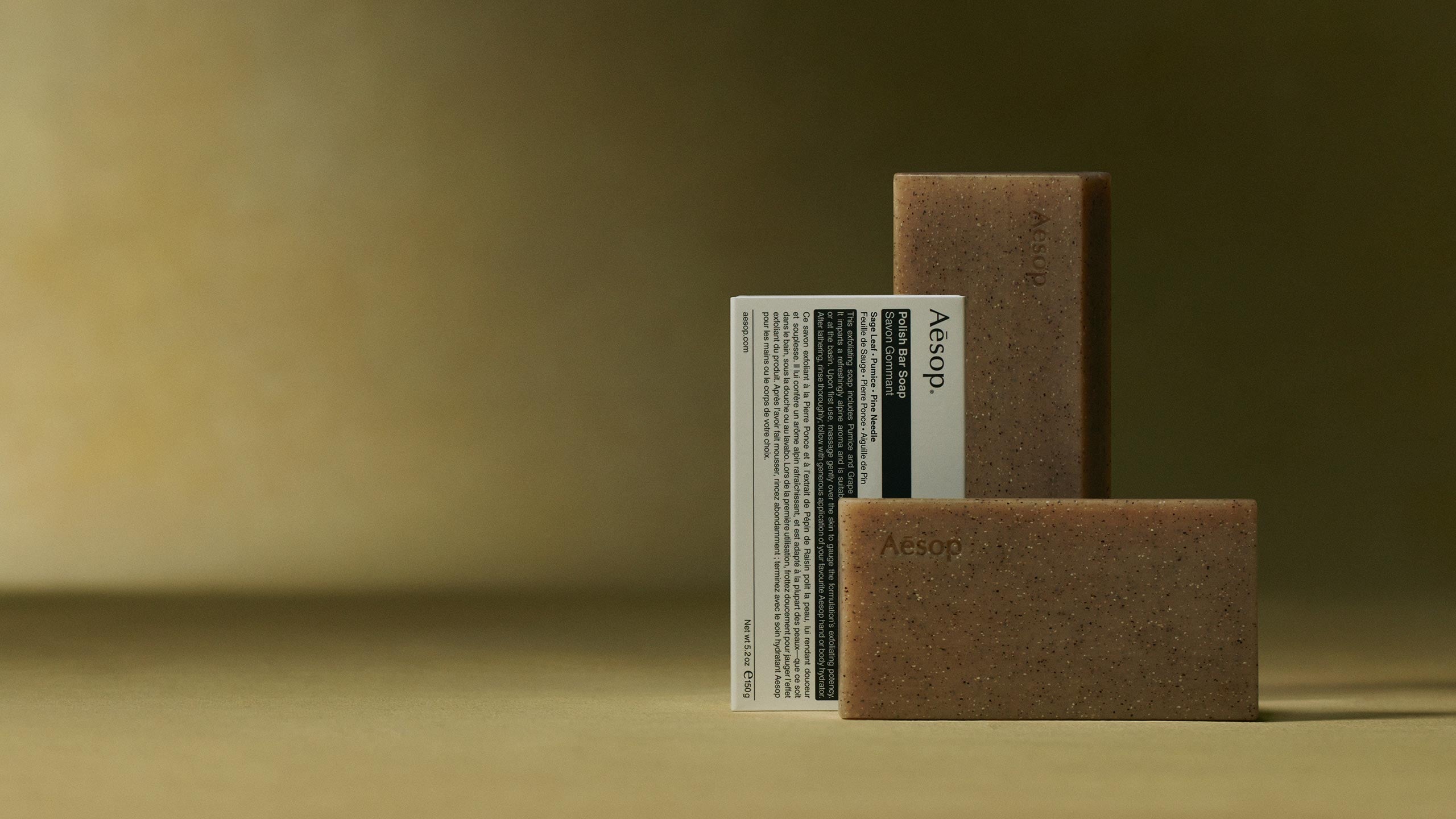 Aesop polish bar soap and its packaging placed in front of green textured background