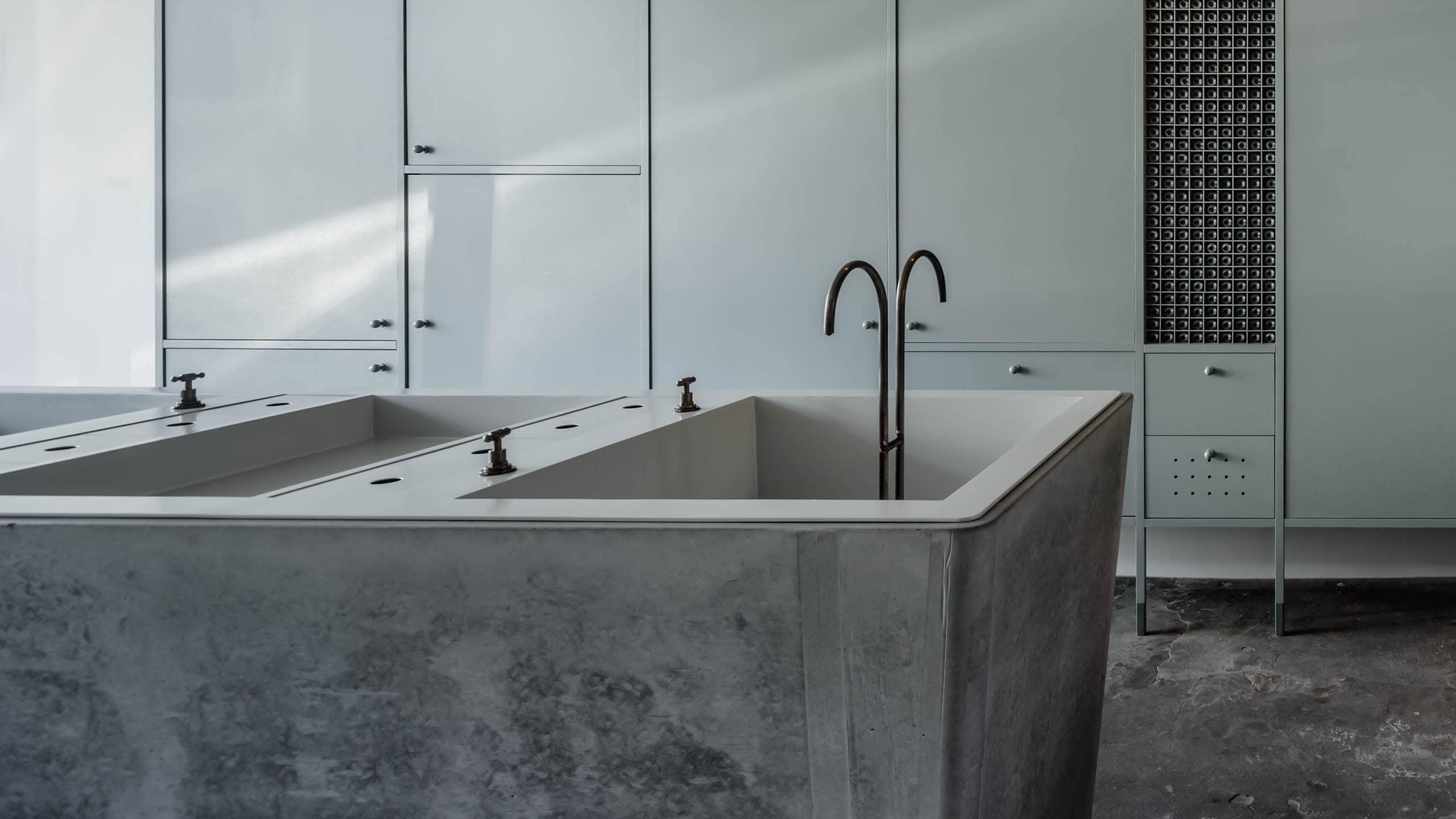 The refurbished laundry basin that acts as the customer experience basin. It's concrete construction compliments the surrounding soft green cabinets.