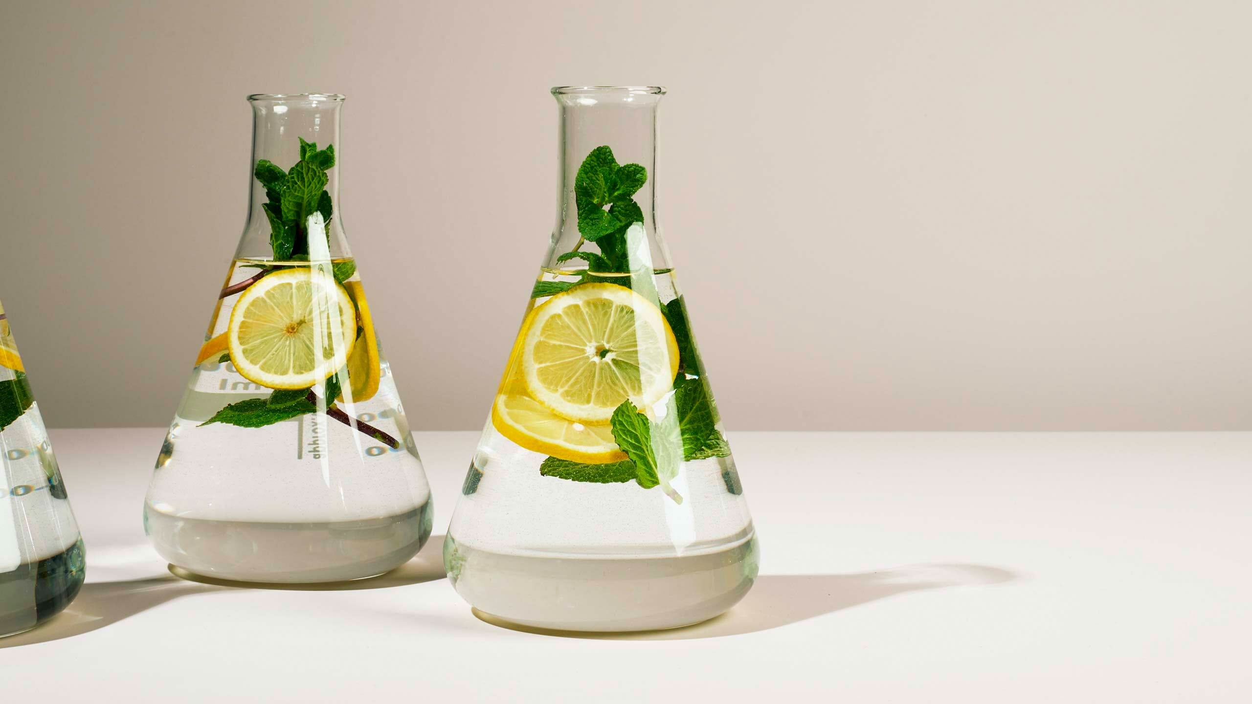 Three large glass beakers filled with water, sliced lemon and mint sprigs.