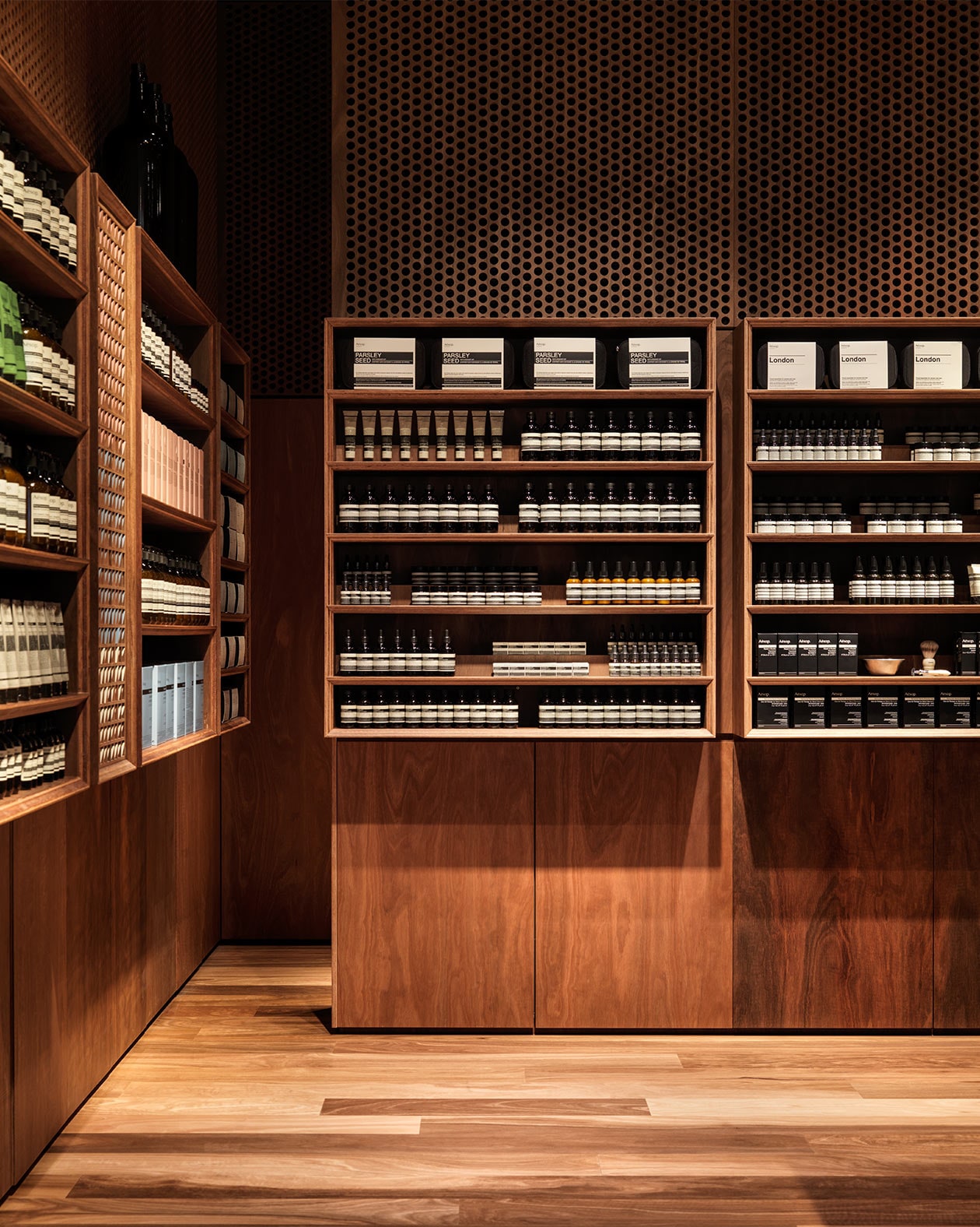 Dark timber shelving displaying several Aesop products. 