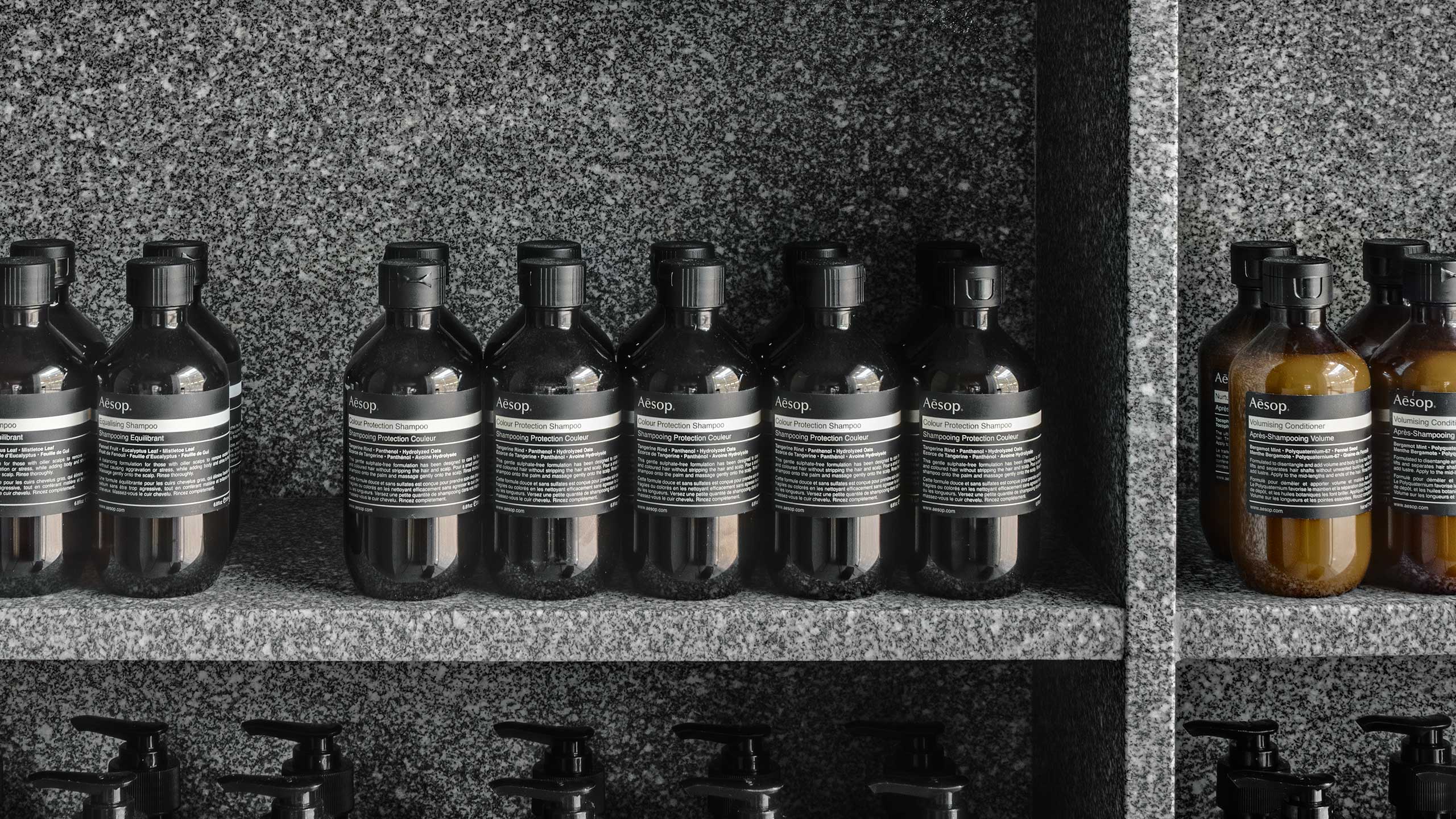 Close-up of Aesop Product sitting inside concrete shelves. 