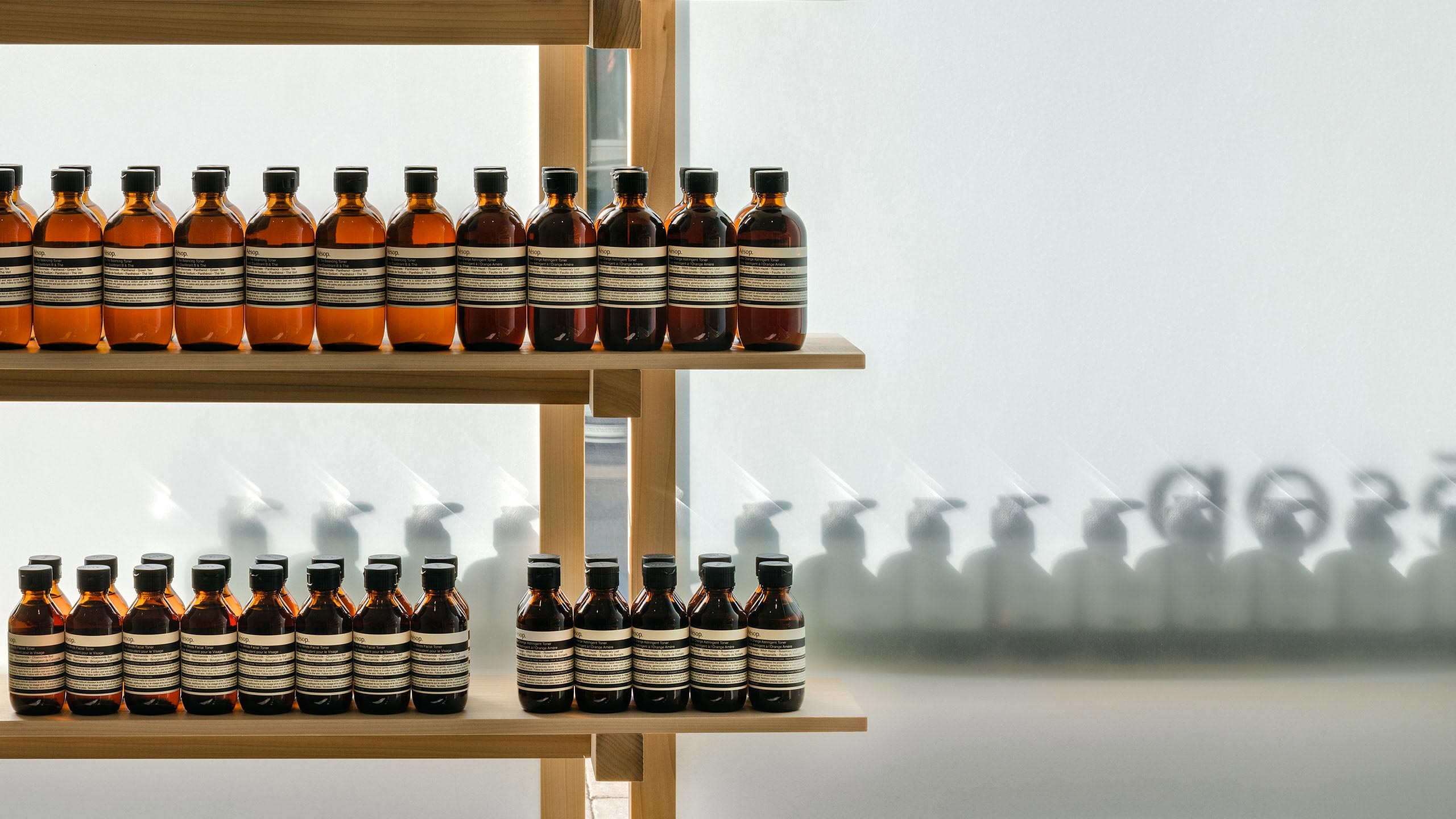 Aesop product lined up neatly on a brightly lit wooden shelf.